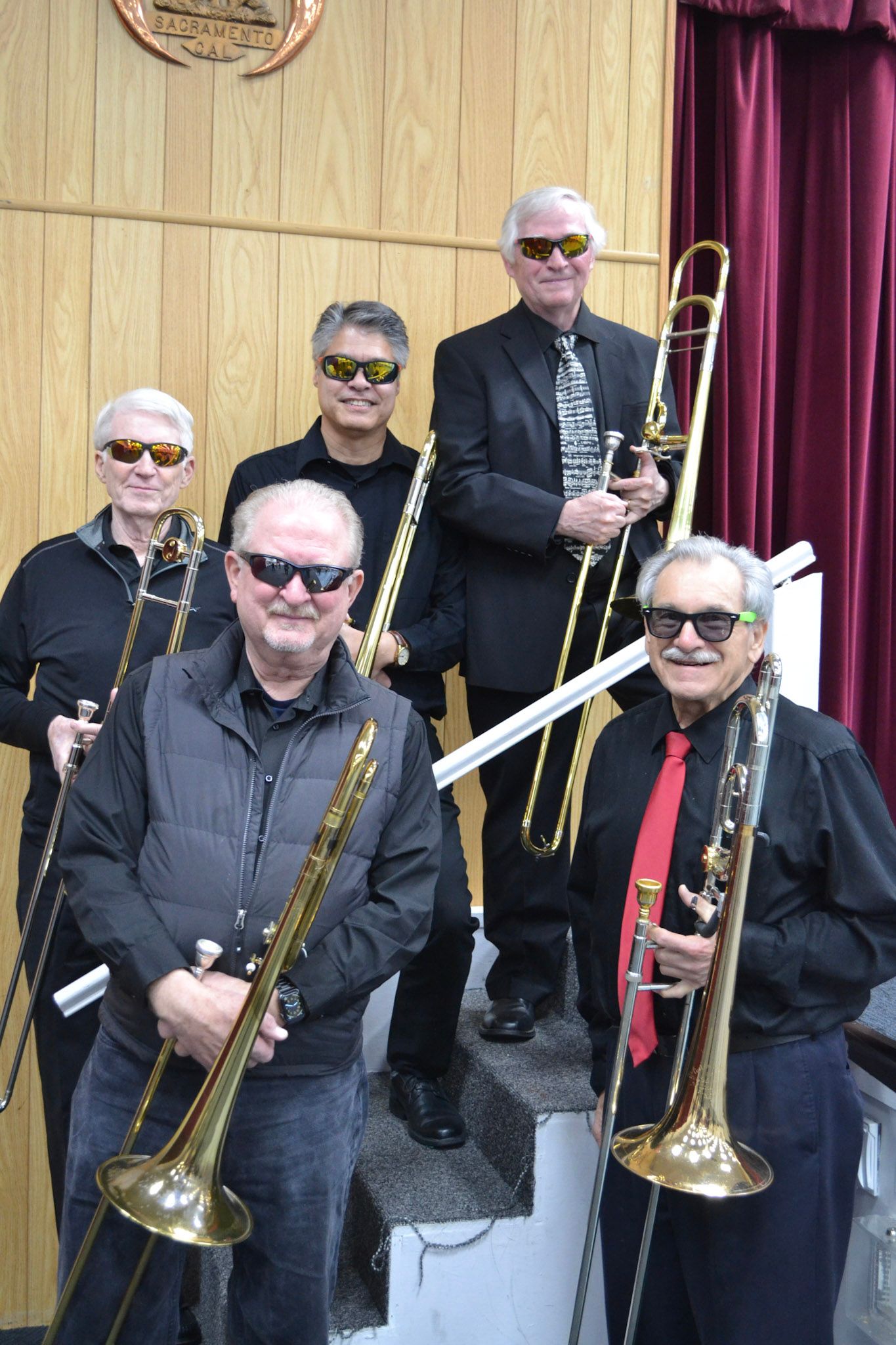 The trombone section posing playfully in sunglasses with their trombones