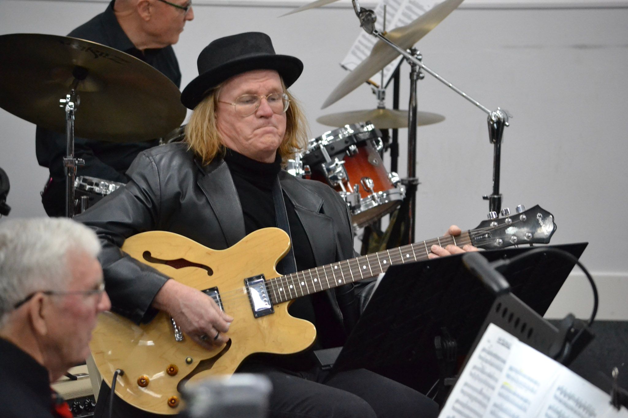 A SwingMasters guitarist in a black hat and leather jacket playing electric guitar