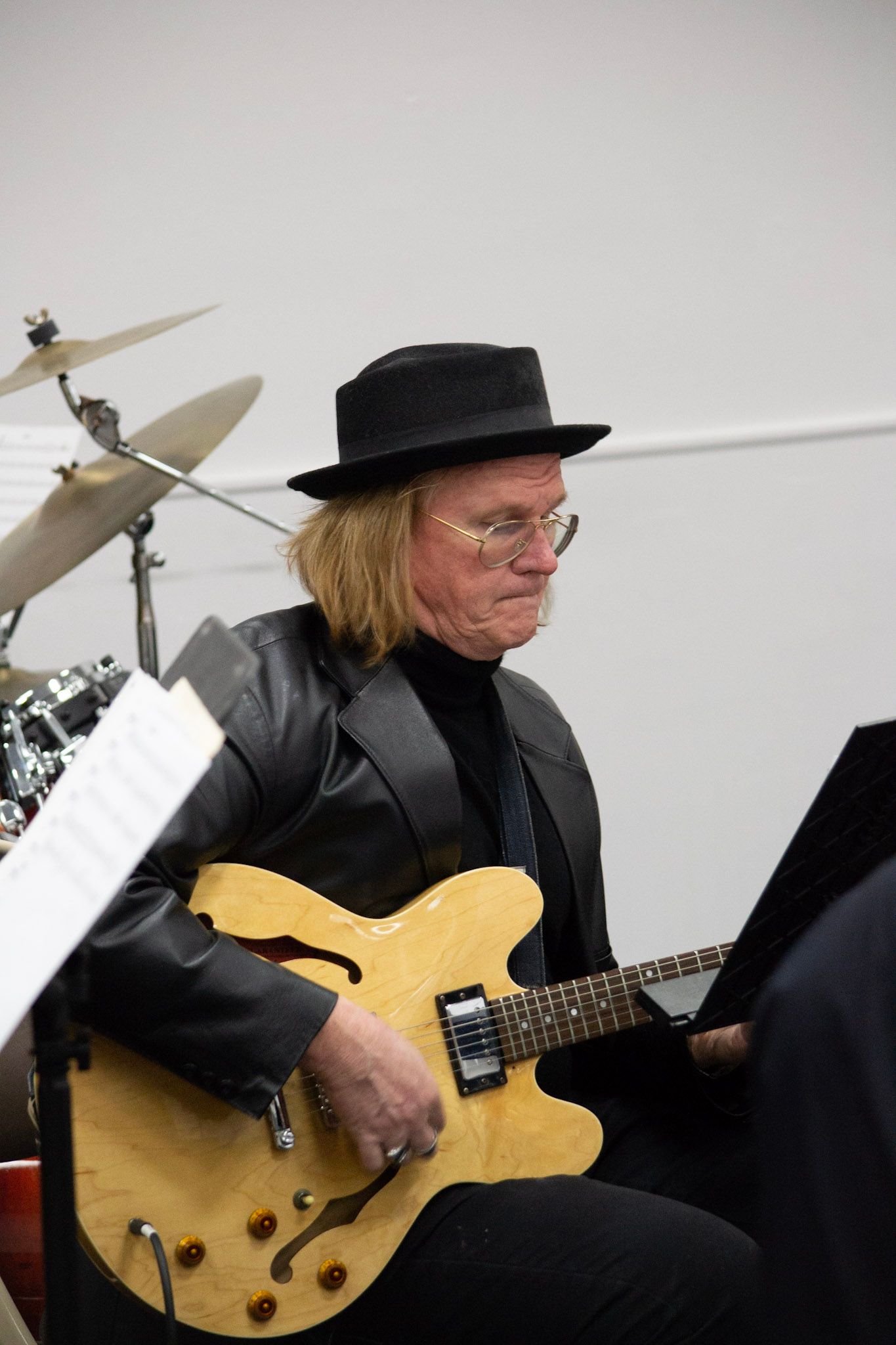 A SwingMasters guitarist performing during a rehearsal, seated near the drum kit