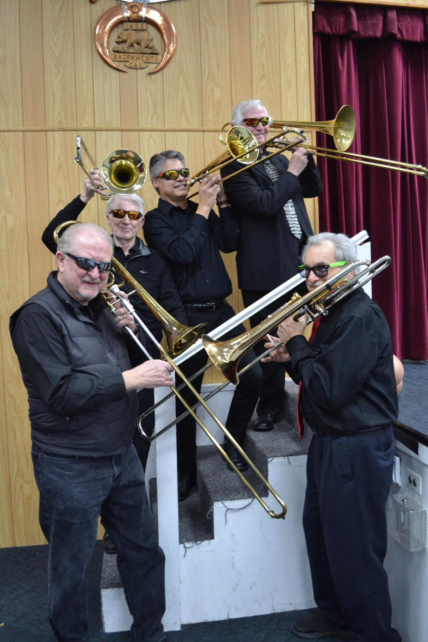 Trombone players crossing their instruments for a playful group photo