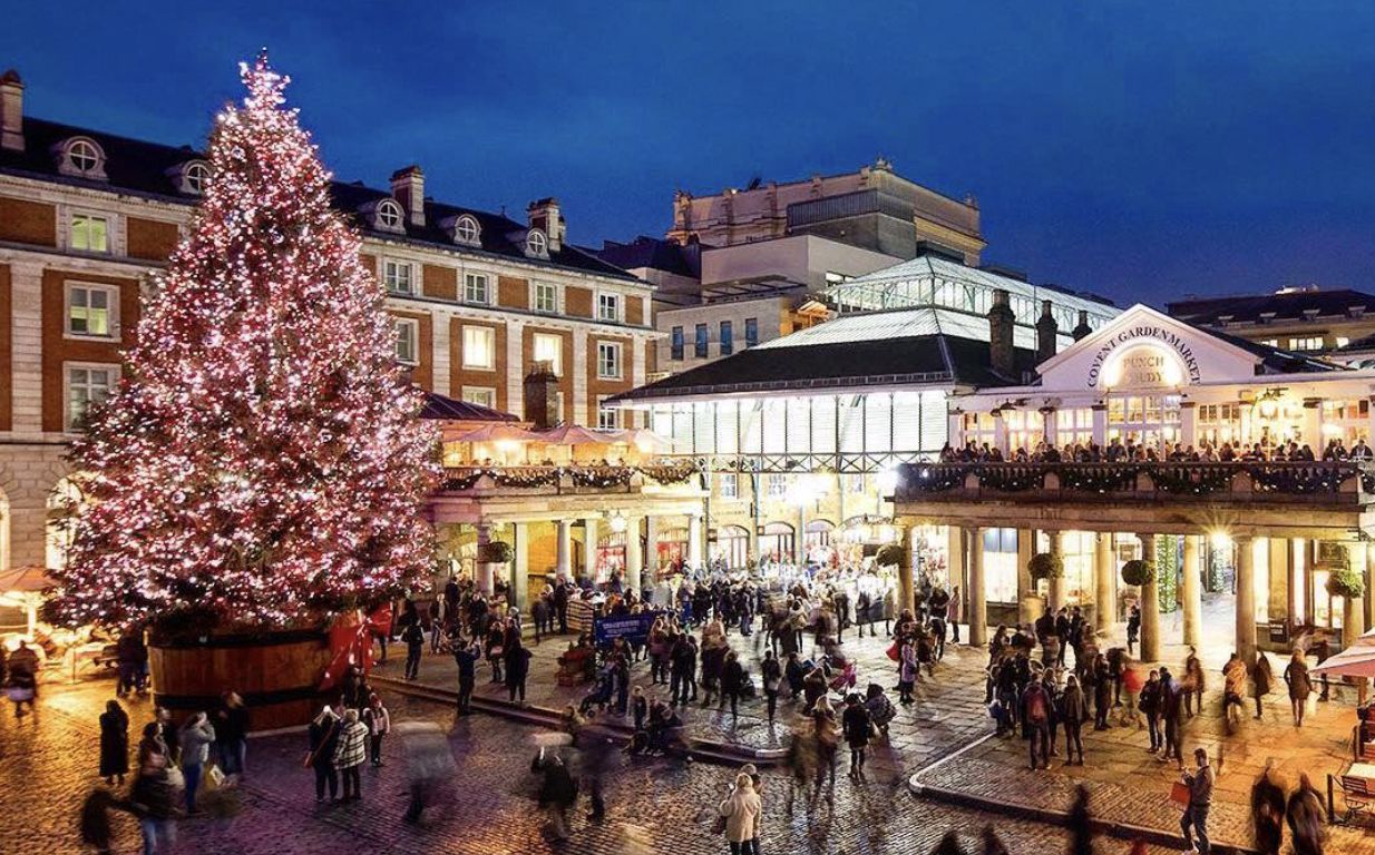 A winter shopping scene with stores lit up a Christmas tree and shoppers