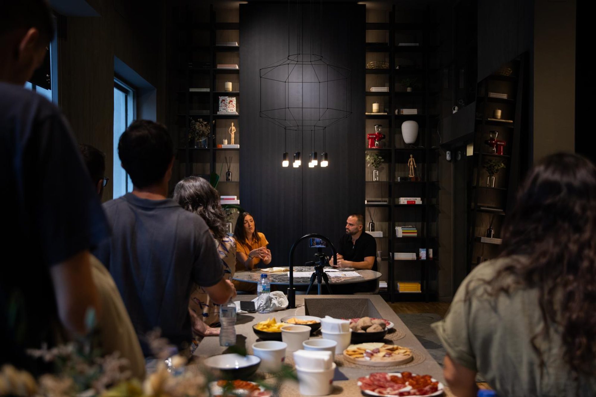 Sara Portela y Carlos Lluna conversan sentados ante una mesa redonda en el showroom de Studio2 durante La ciudad que habitamos.