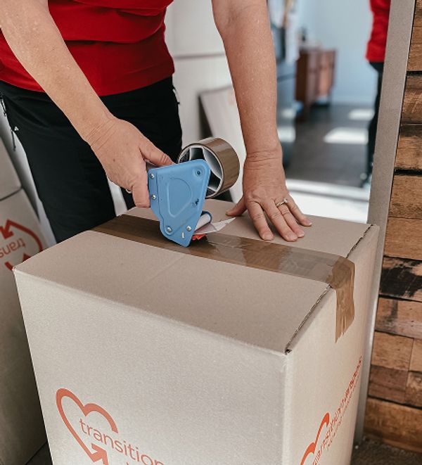 Transition Angels team member taping a packing box