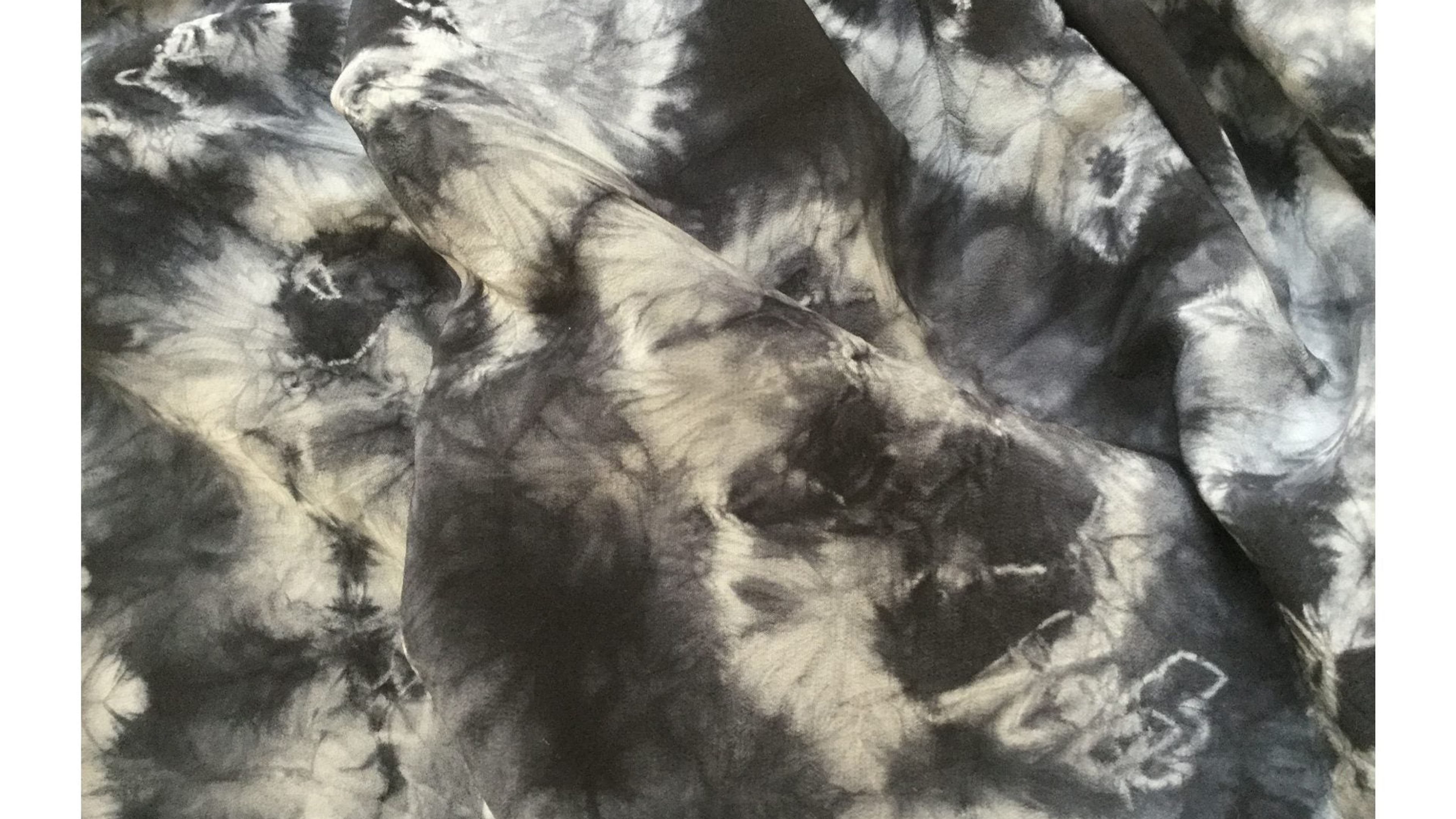 shibori dyed textile. black background white pattern