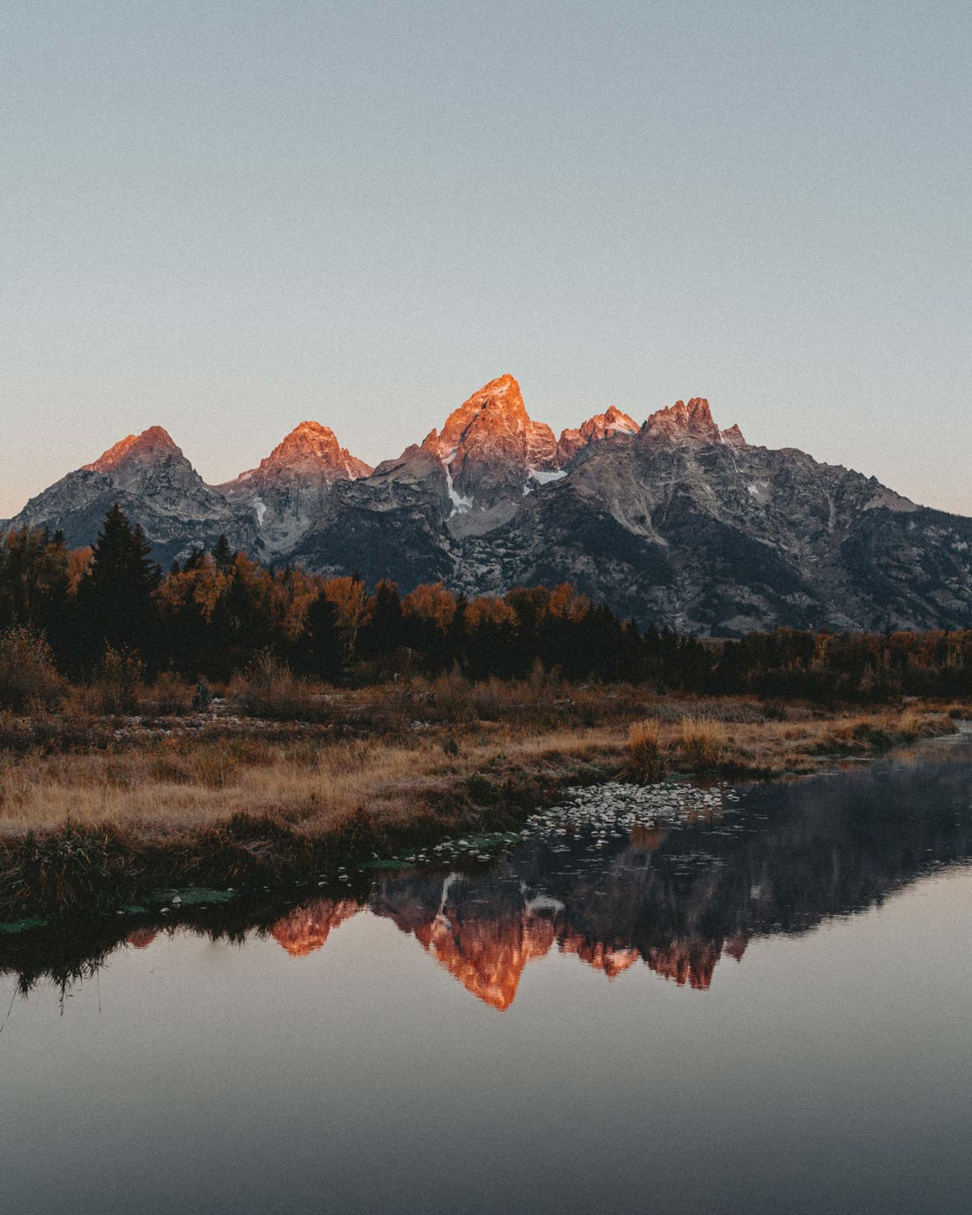 Grand Teton peaks glowing over still water