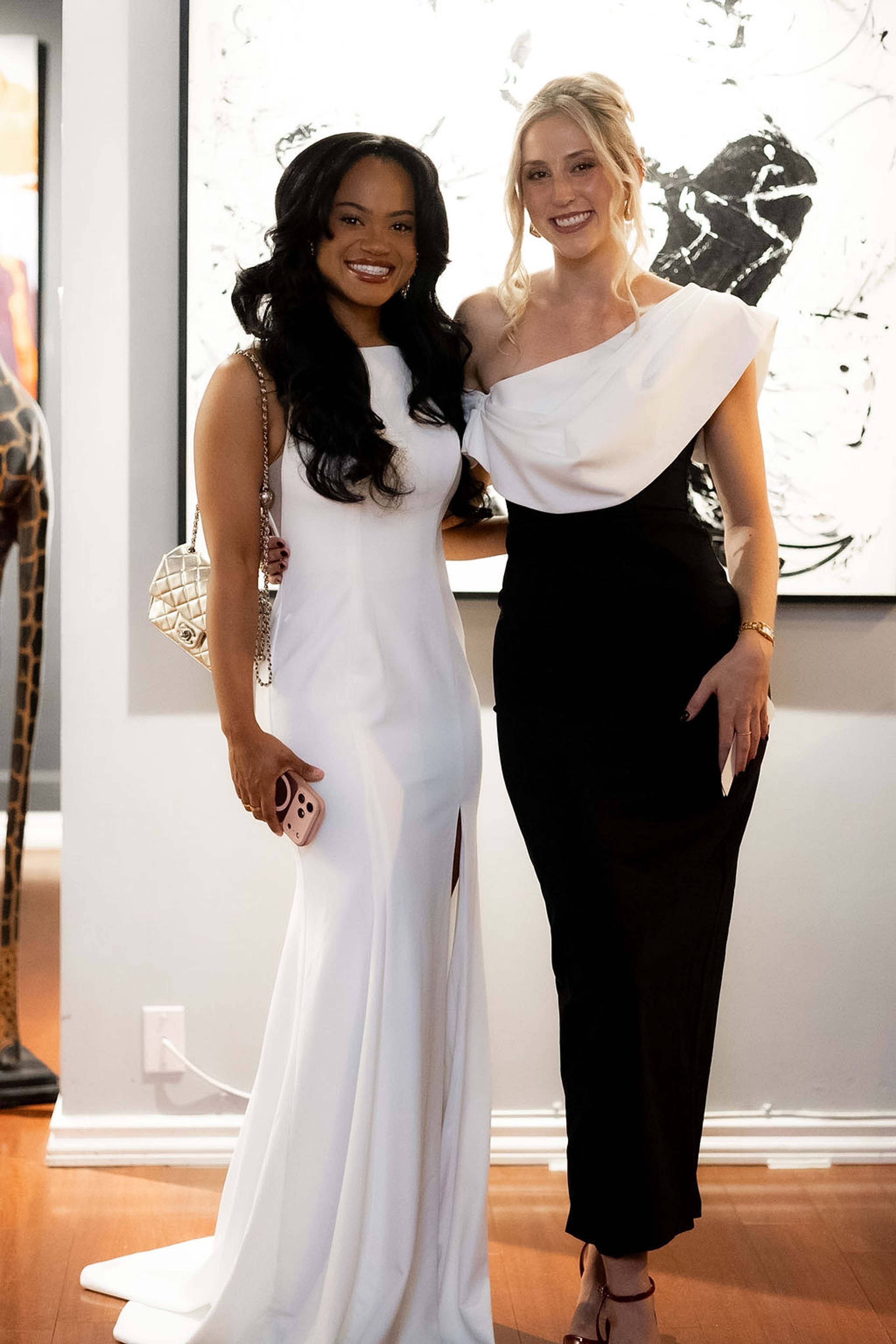 Two guests posed in front of a black and white abstract painting