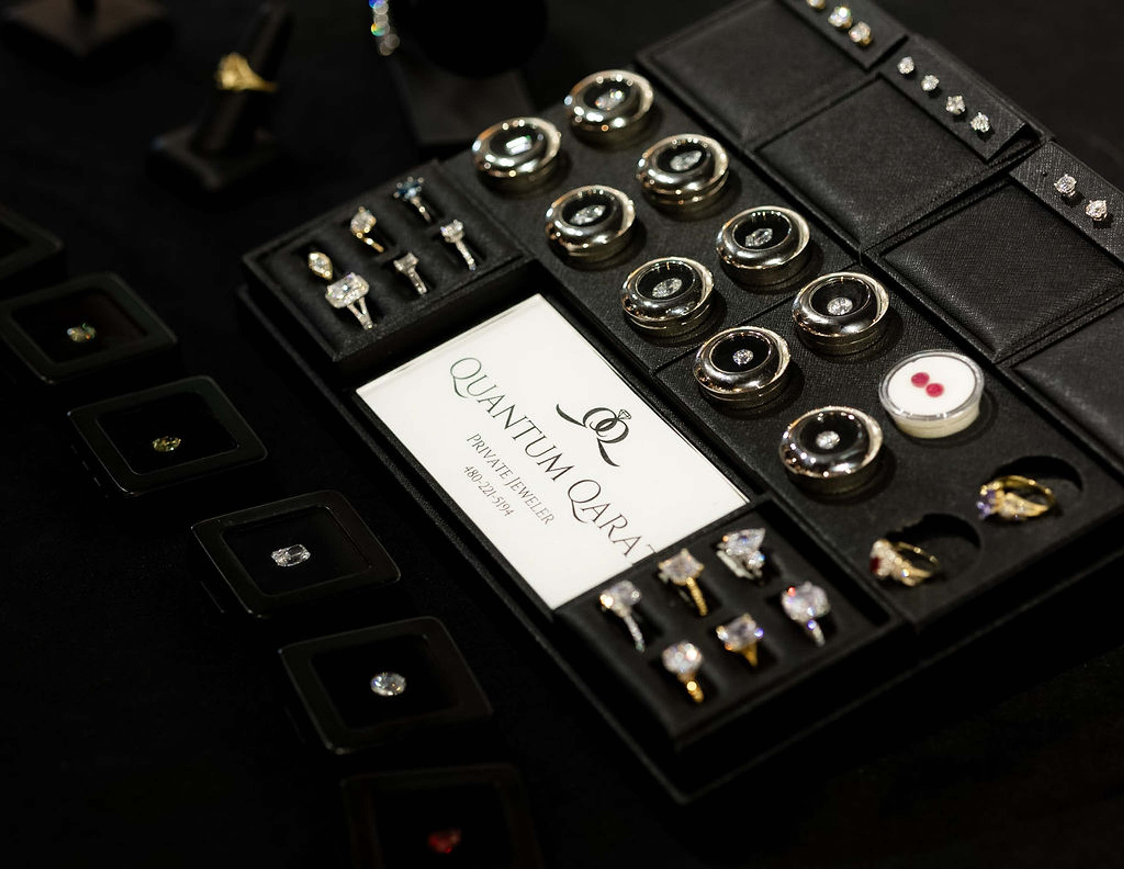 A jewellery display tray of rings and earrings beside a Quantum Quartz branded card
