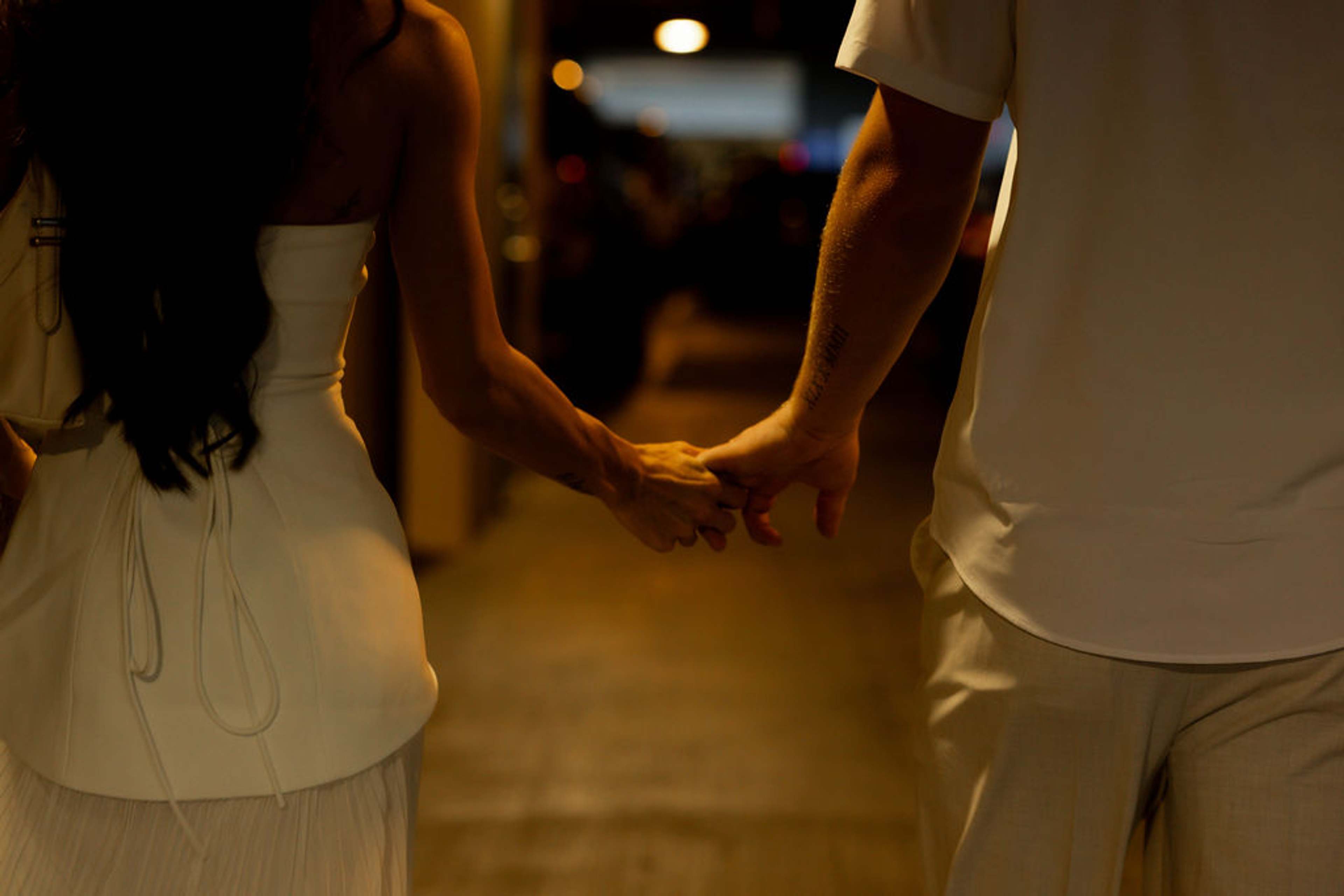 Backlit detail of two hands joined in a warm corridor of amber light