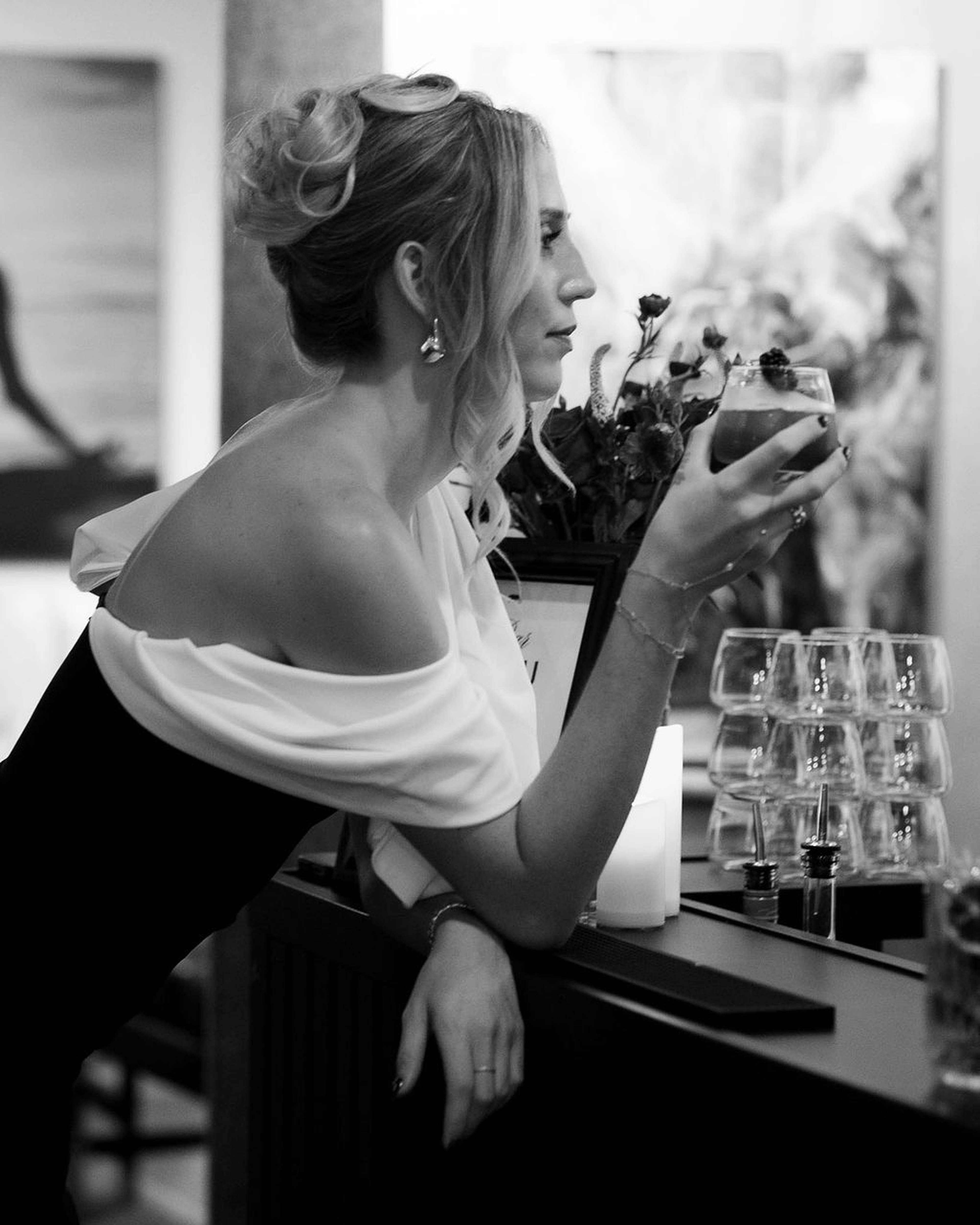 Guest sipping a cocktail at the bar beside stacked glassware