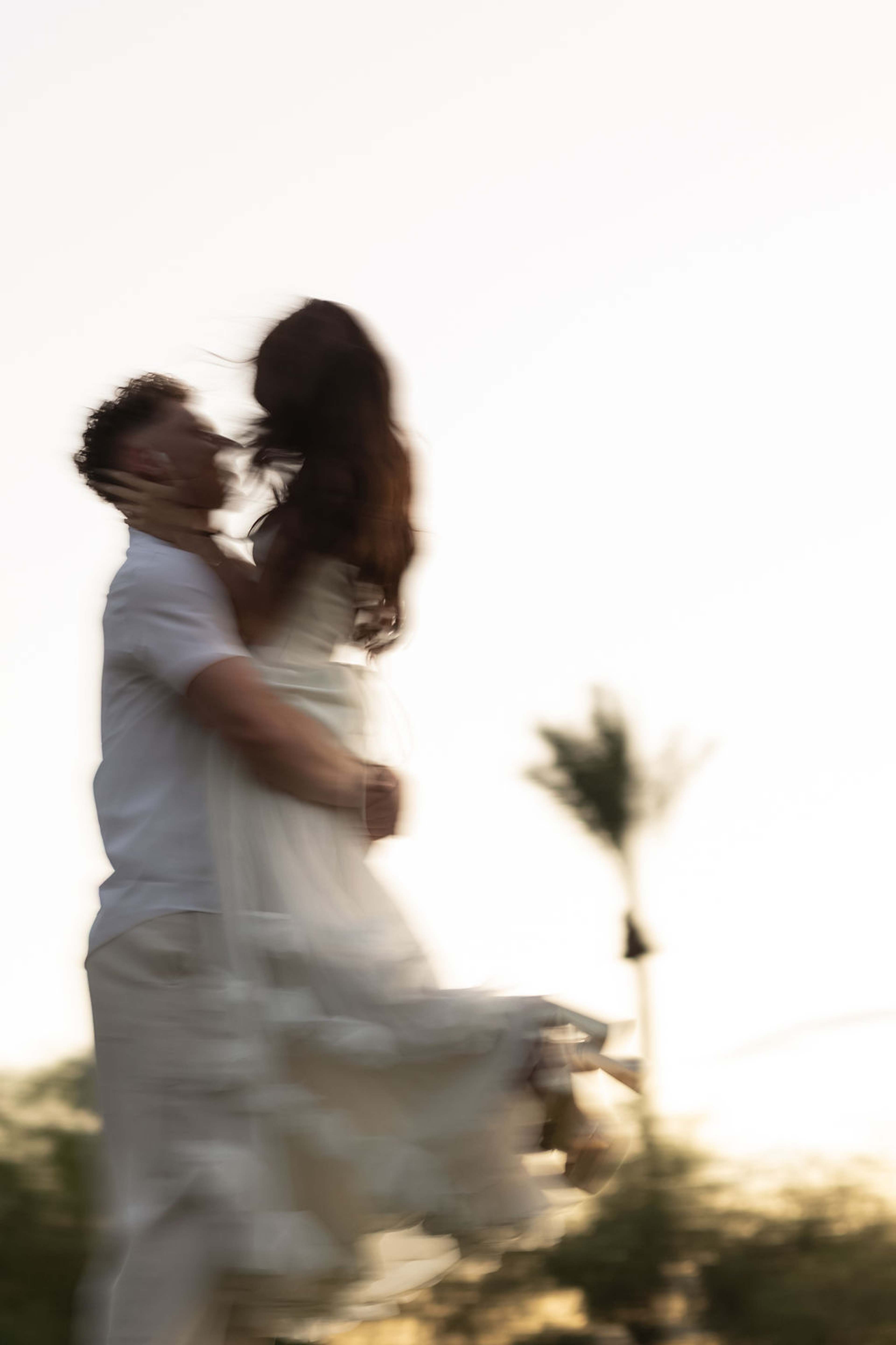 A long exposure of a couple turning together, the movement blurring into warm desert light