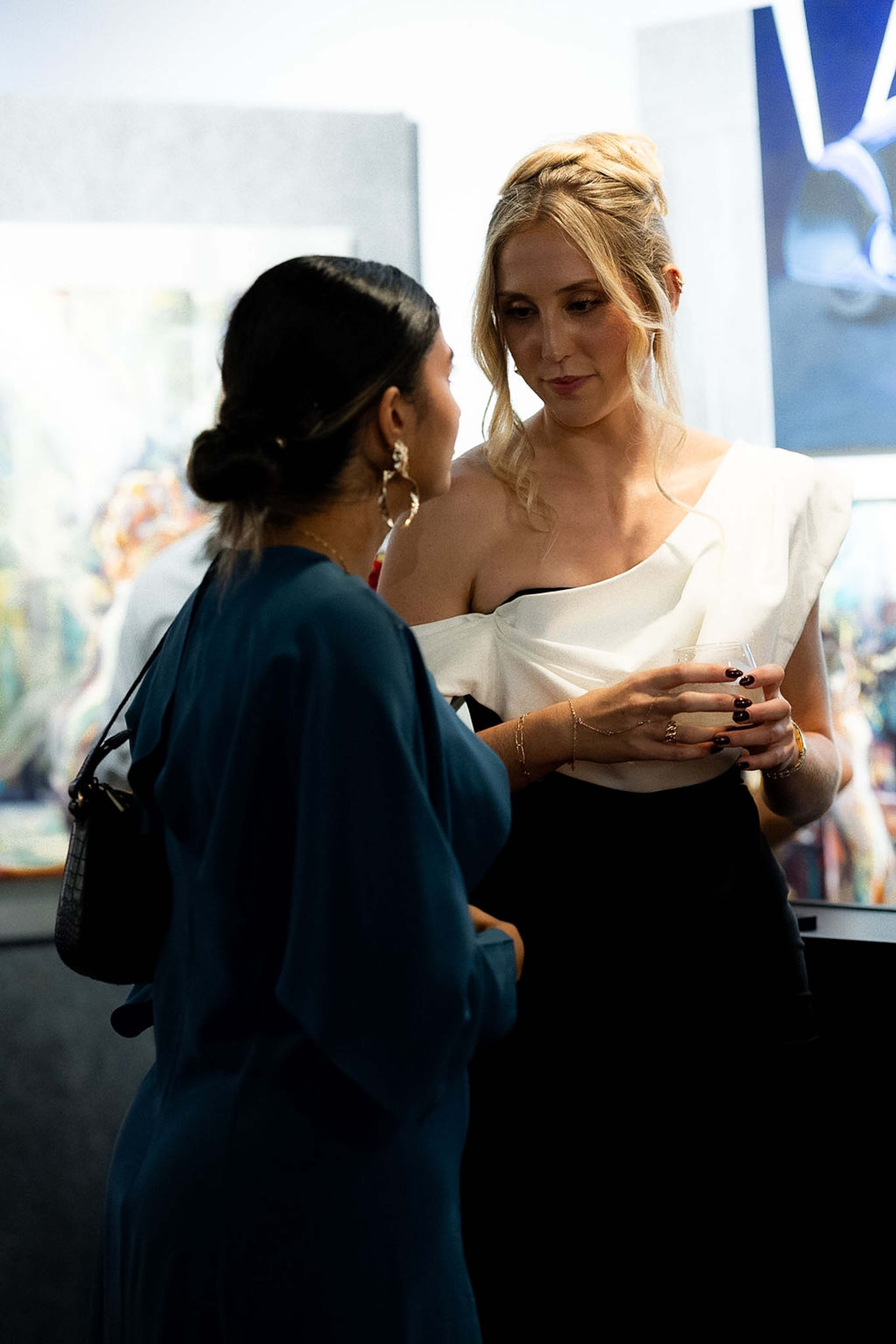 Two guests in conversation, one in a teal dress