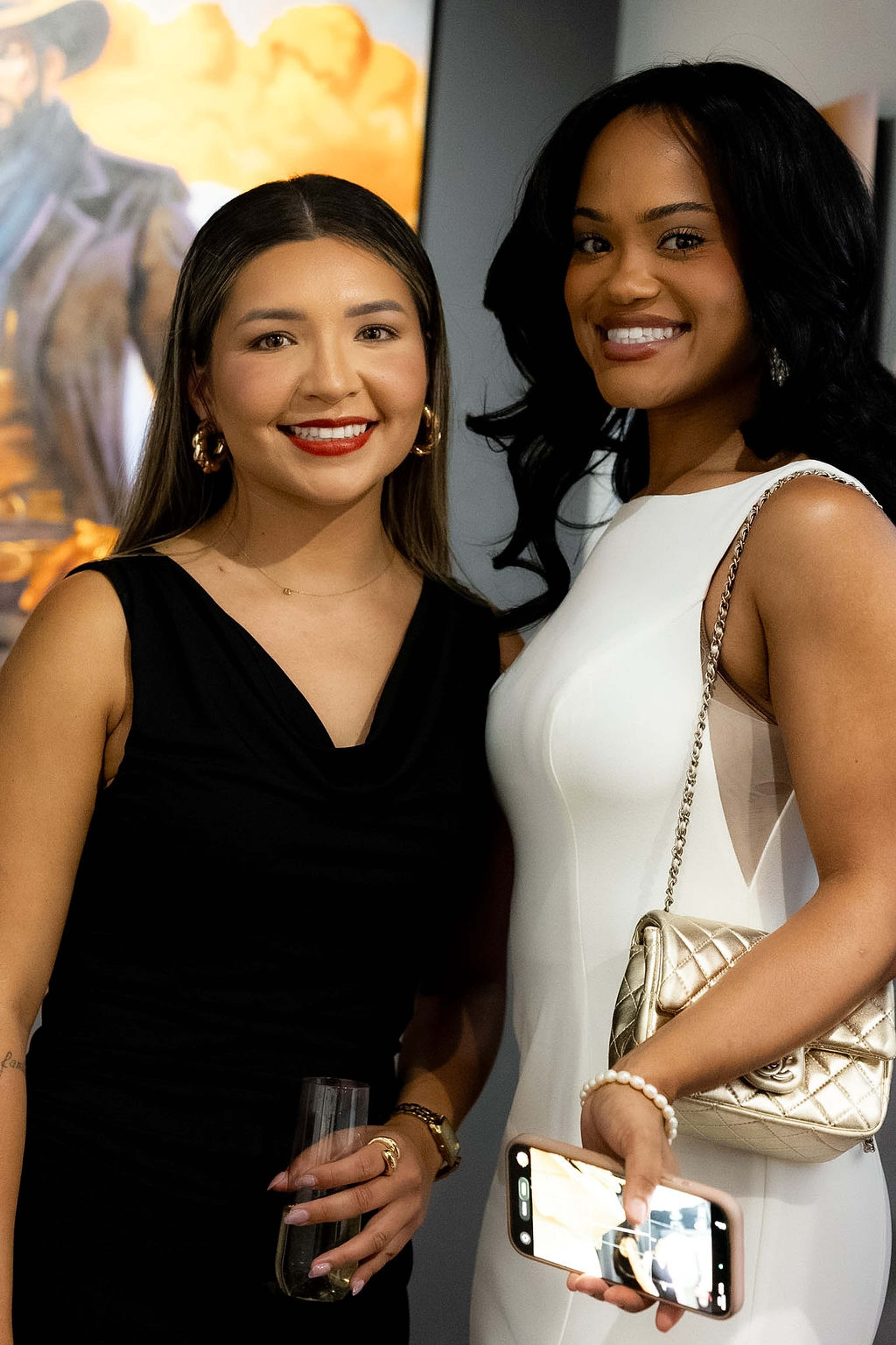 Two guests posed together, one holding a phone