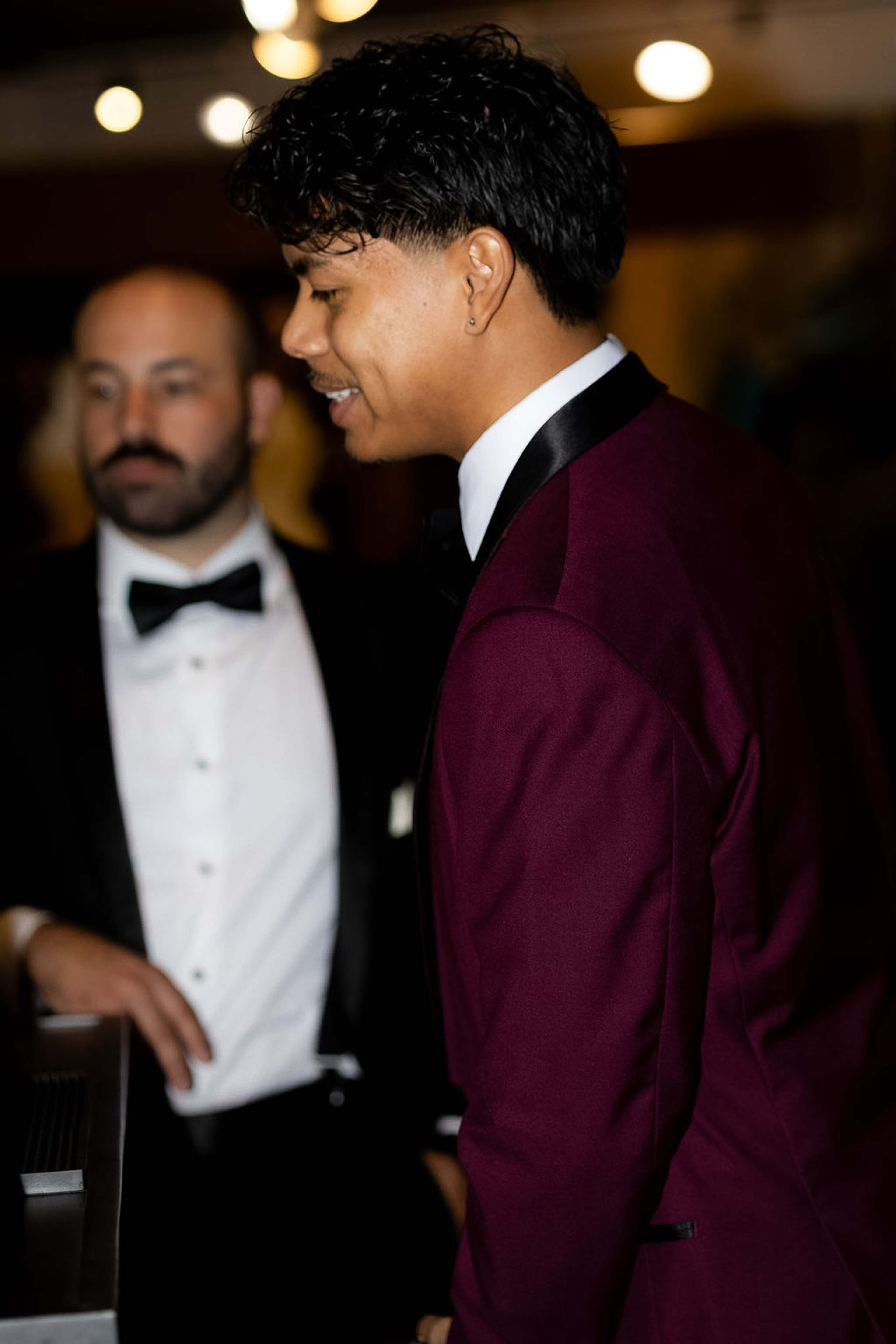 Guest in a burgundy dinner jacket, another in black tie behind