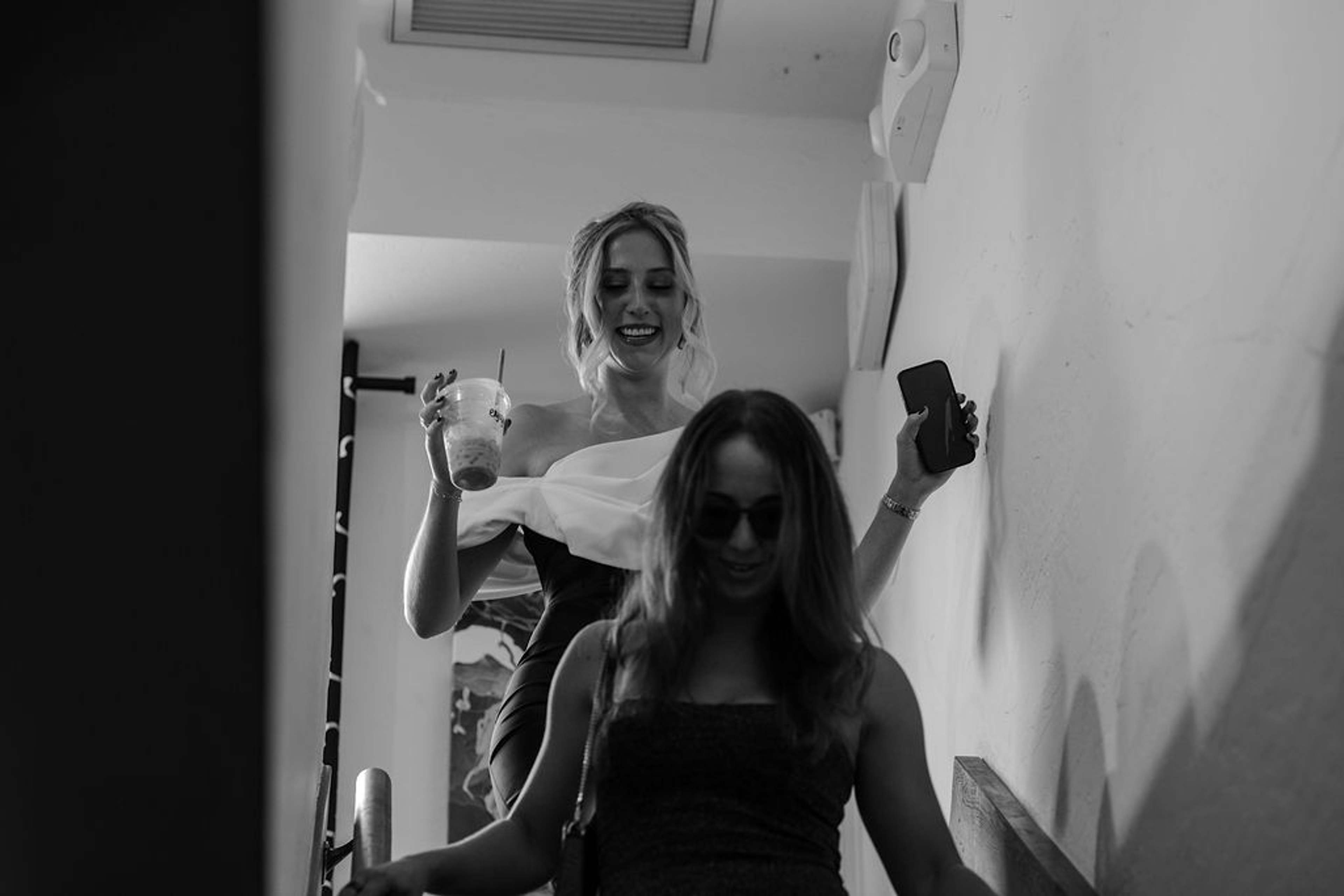 Two guests on the staircase, one laughing with a drink in hand