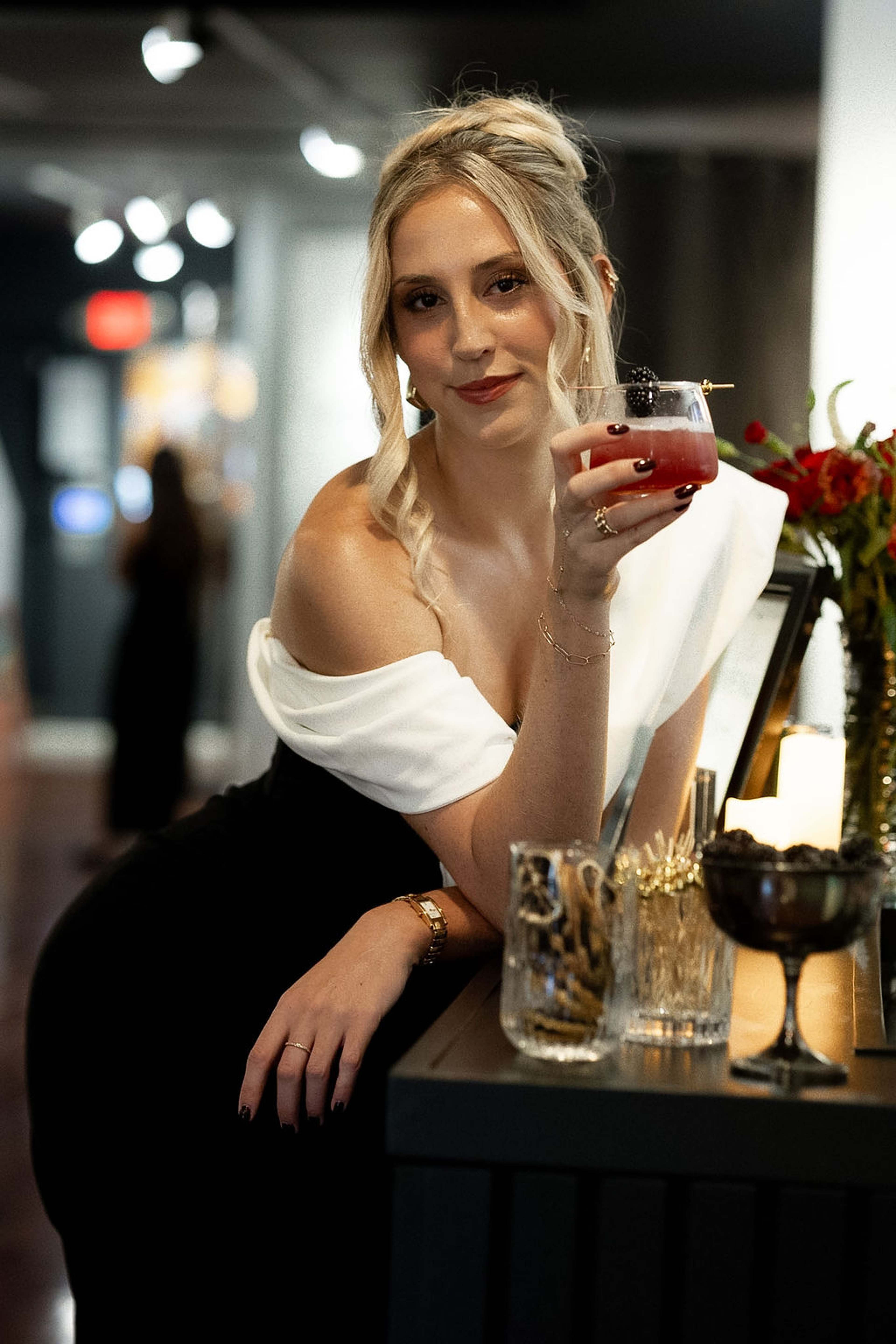 Guest in an off-shoulder white and black gown leaning on the bar with a cocktail