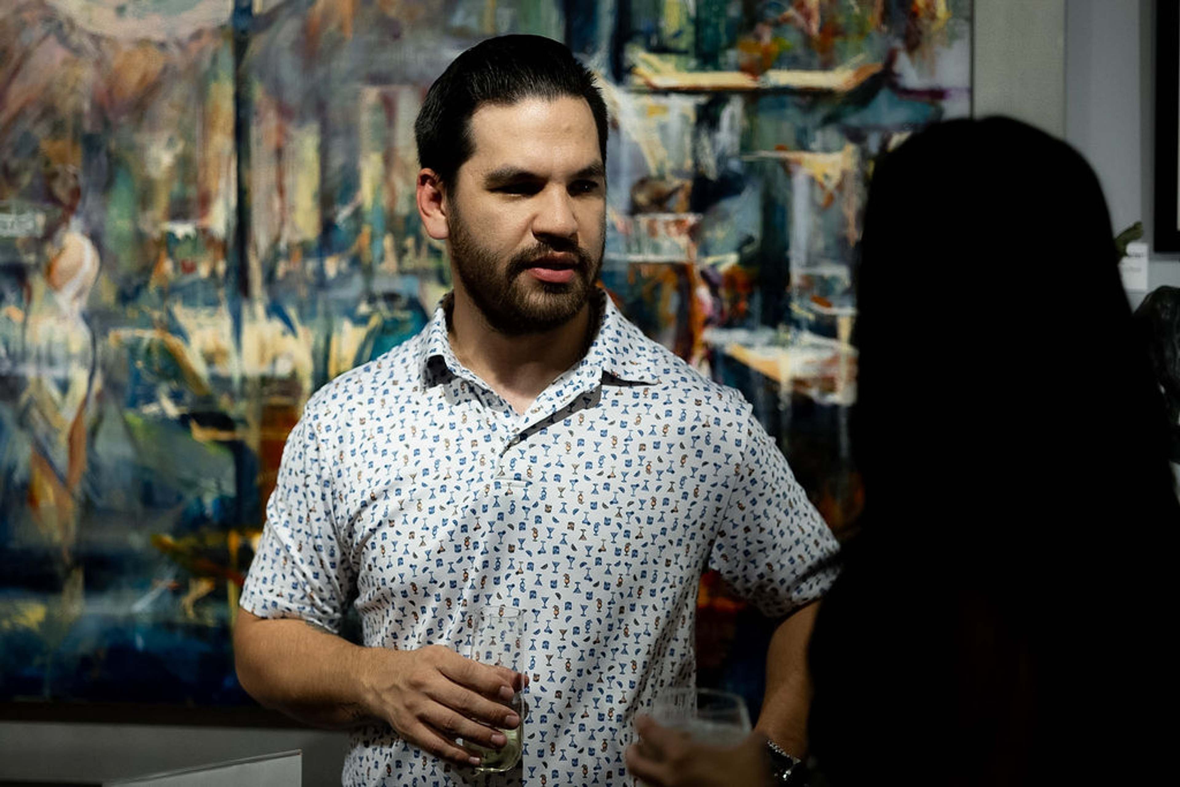 Guest in a patterned shirt in conversation, artwork behind