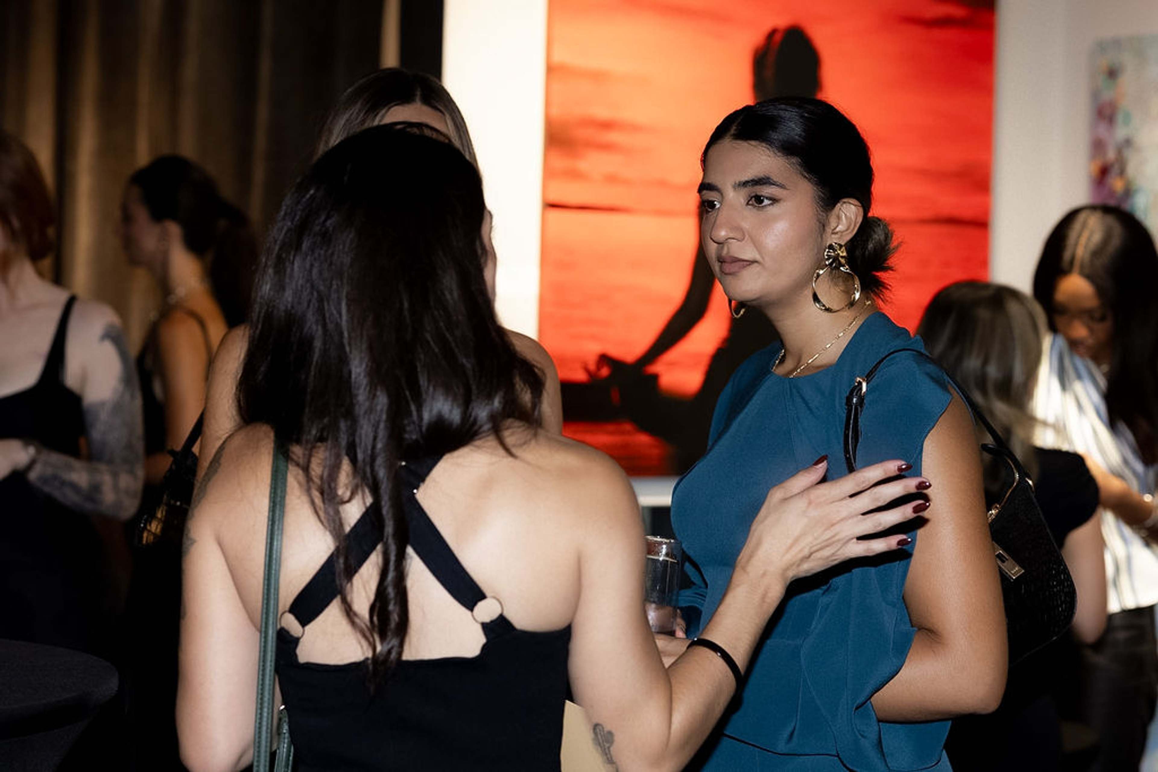 Two guests in conversation in front of a red painting