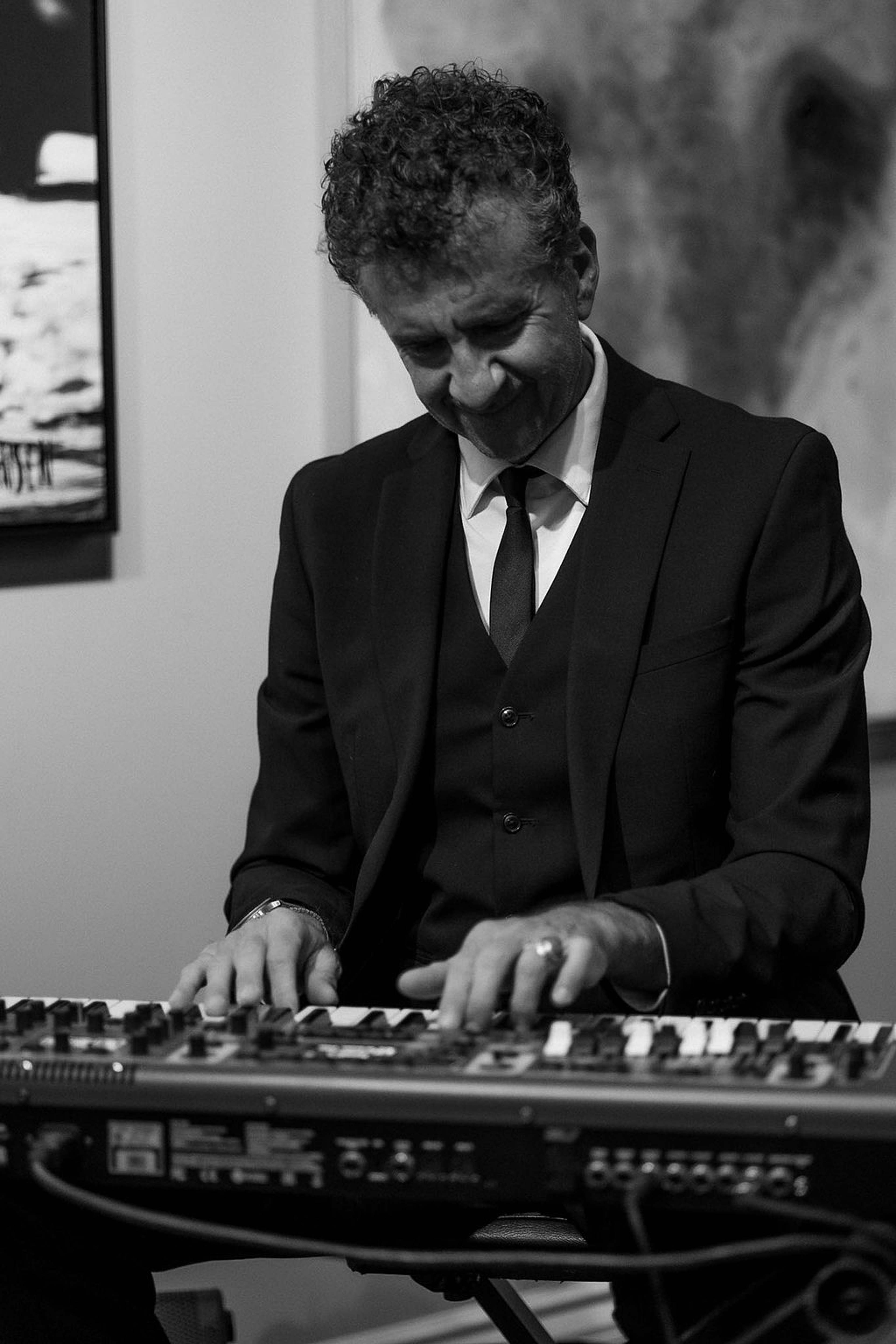 Musician at the keyboard, head bowed over the keys
