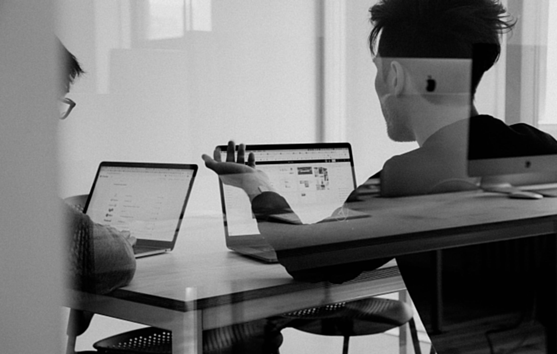 Two colleagues working on their laptops around a table