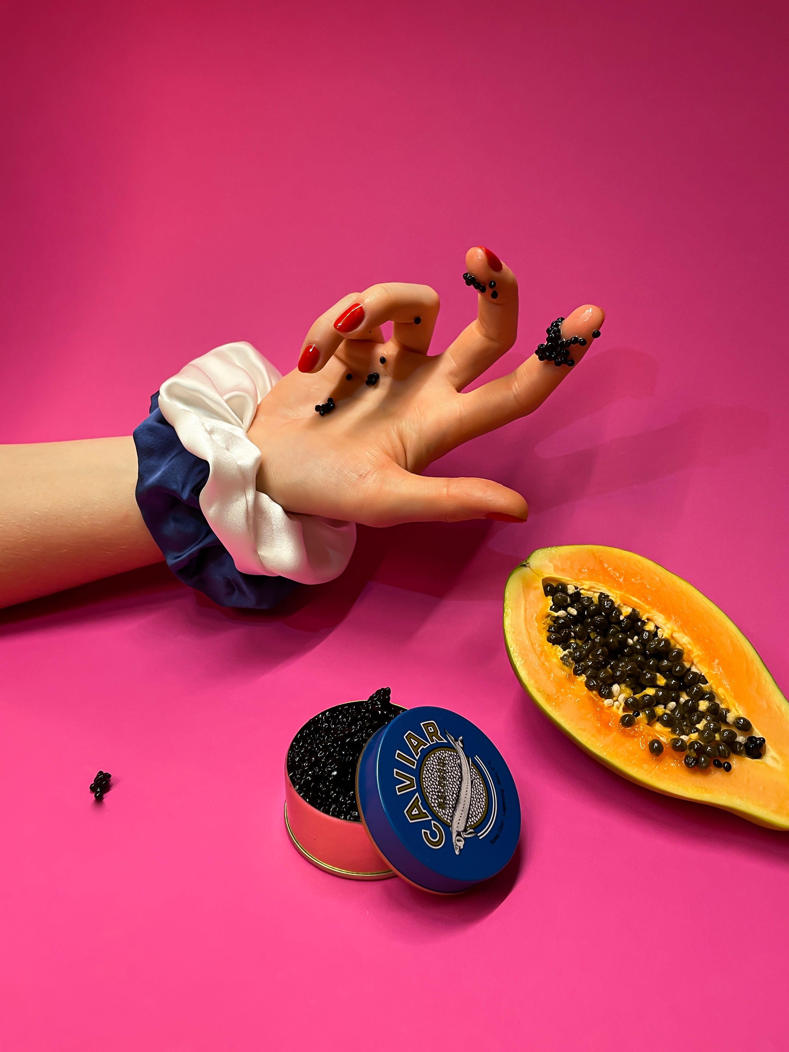 Wrist with Silk crunchies. Finger dipped in caviar. Papaya fruit.