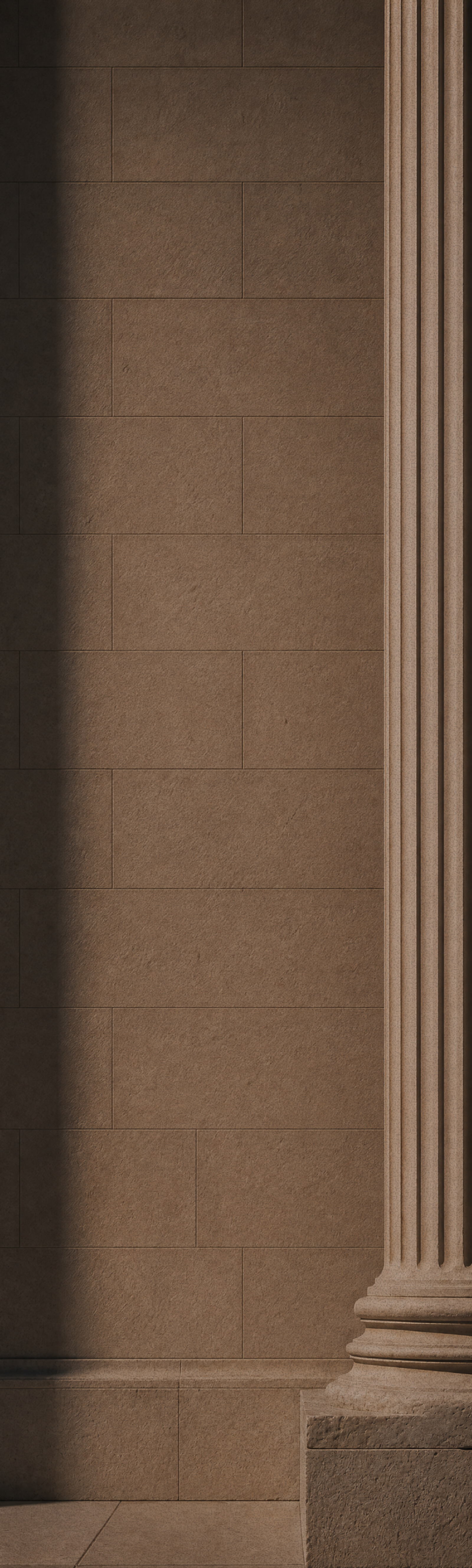 Brown stone wall with a fluted column on the right and a shadow on the left.