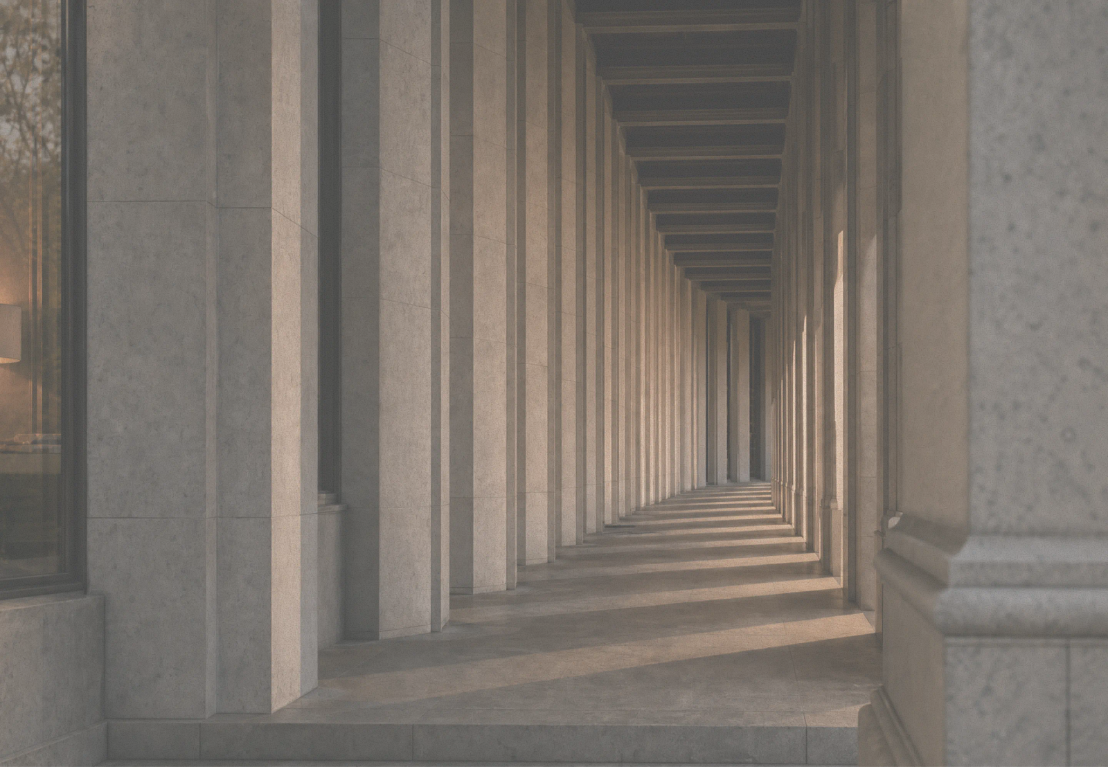 A long stone colonnade with light casting strong shadows.