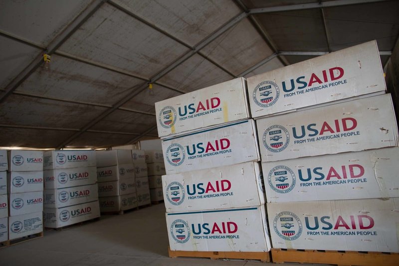 Boxes marked with USAID pilled in a warehouse (Ellie Van Houtte/USAID)