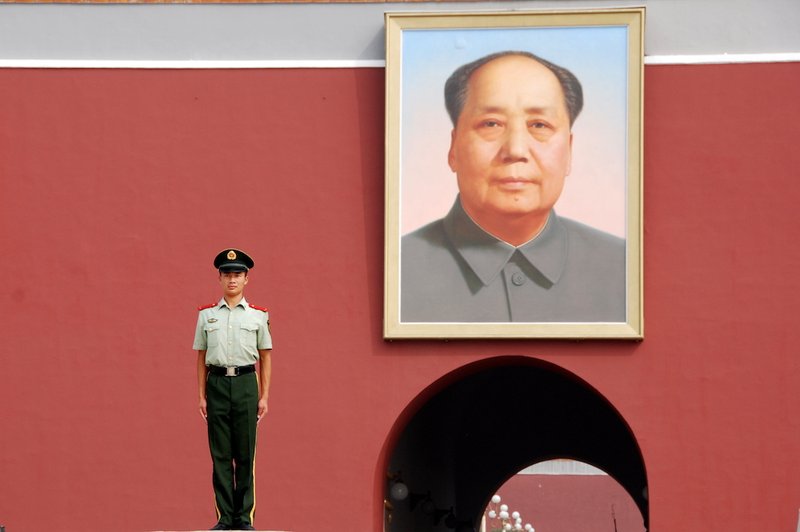 Guard standing beside portrait of Mao Zedong