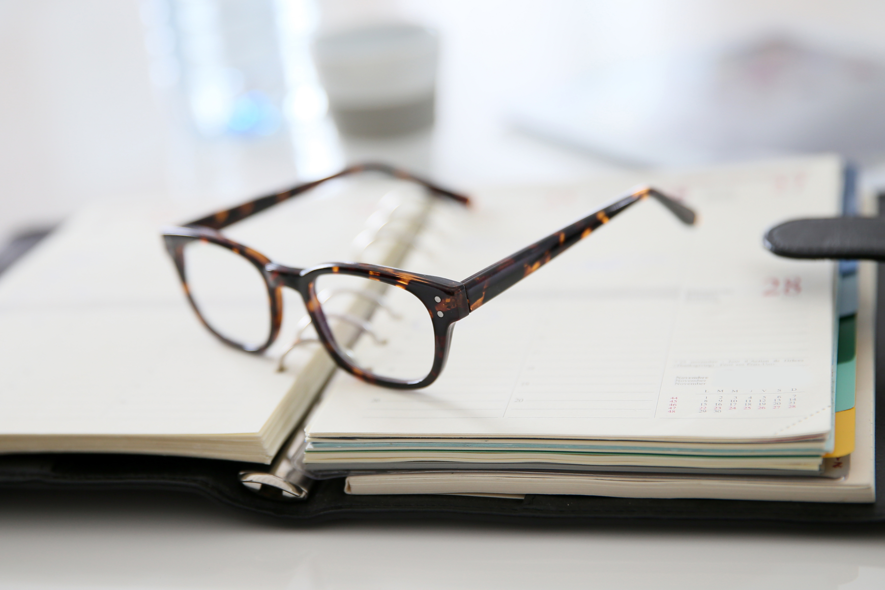 A pair of glasses resting on an open planner.