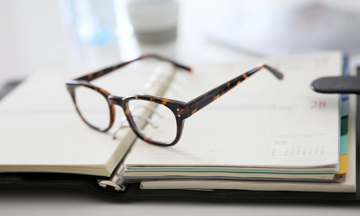 A pair of glasses resting on an open planner.