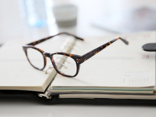 A pair of glasses resting on an open planner.