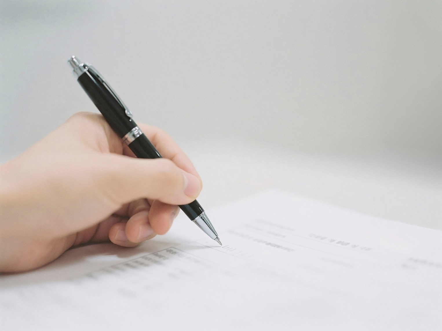 A hand writing on a form with a pen.