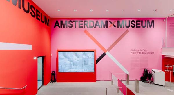 Hall d'entrée coloré du Musée d'Amsterdam avec le logo Amsterdam X Museum sur un mur rose et rouge © Amsterdam Museum