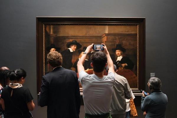Touristes photographiant un tableau classique au Rijksmuseum d'Amsterdam avec leurs appareils modernes.