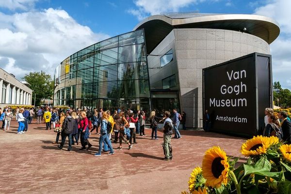 Entrée du Musée Van Gogh Amsterdam avec des visiteurs et des tournesols au premier plan sur la Museumplein © Viator
