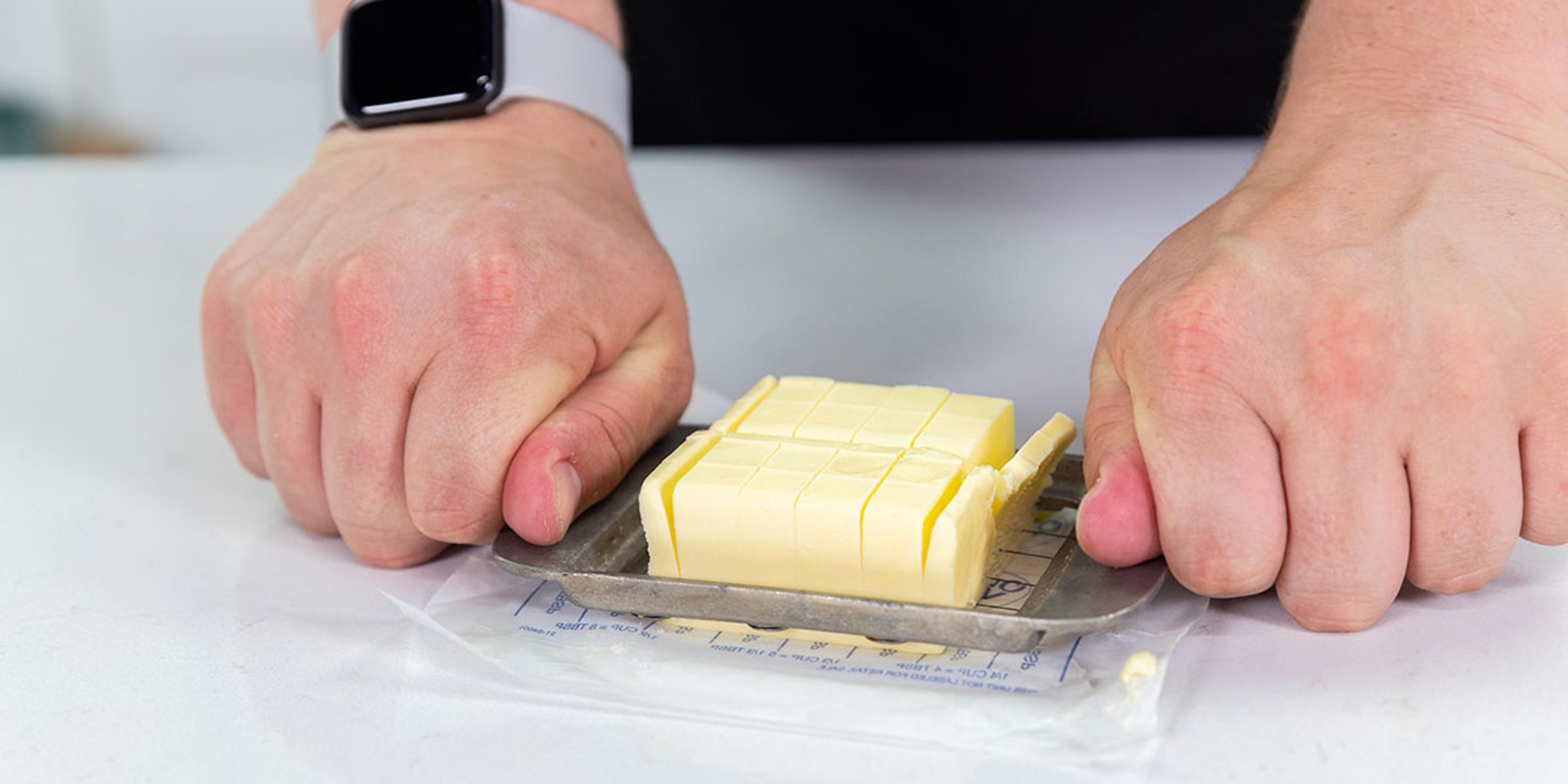 A man pushes a Presto vintage butter cutter down to get chunks of butter.