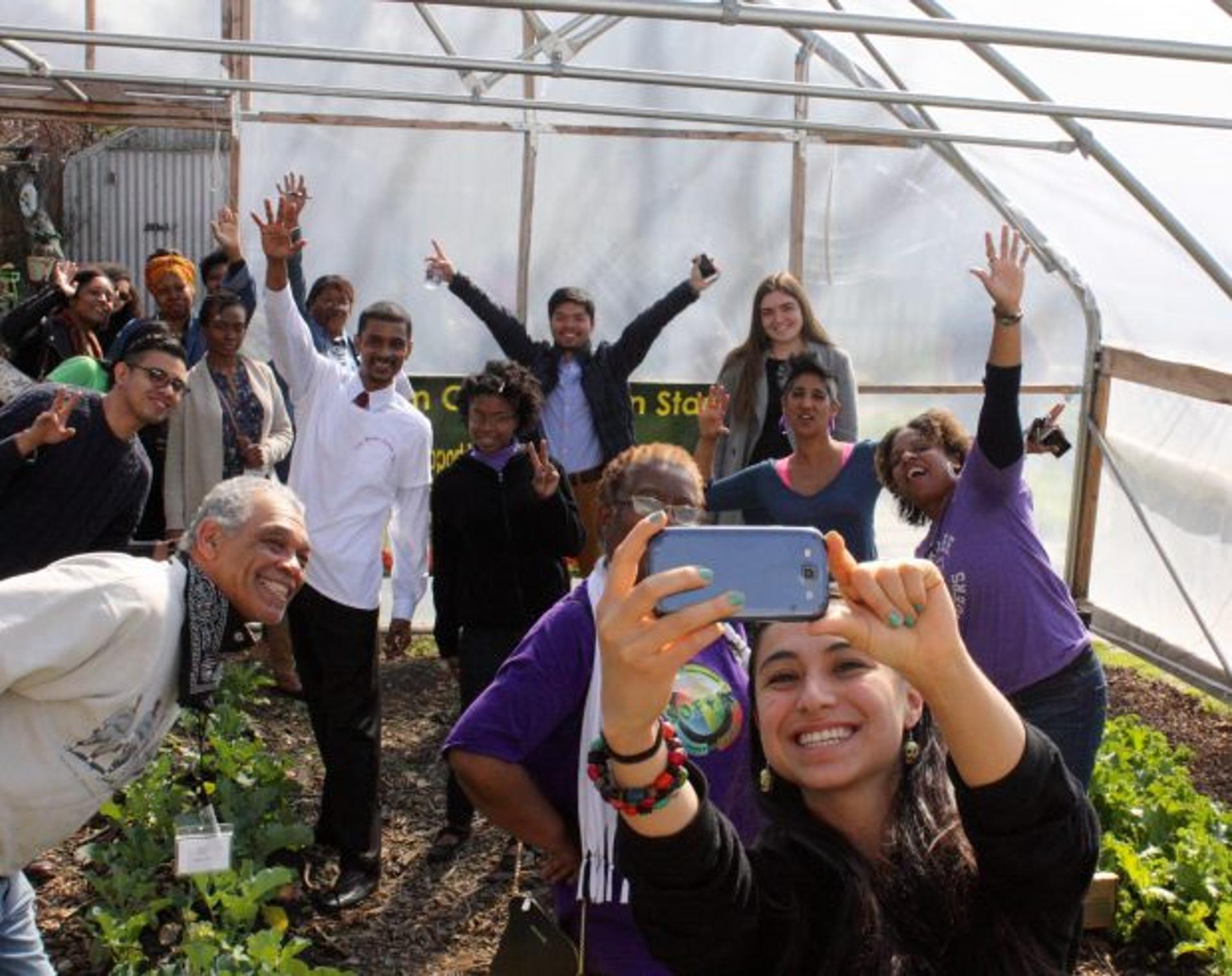People stand in a greenhouse taking a fun selfie.