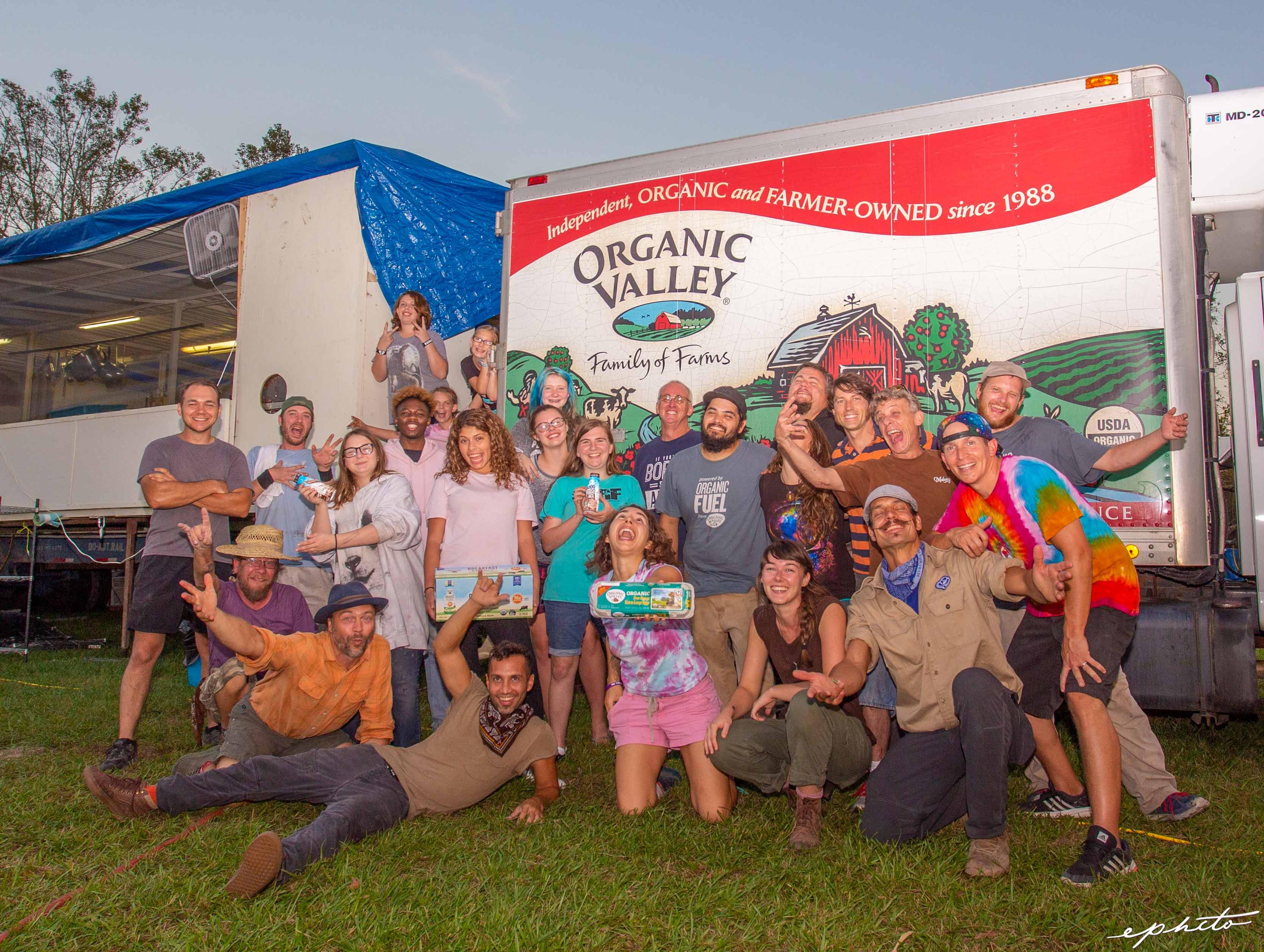 A group of volunteers do a fun pose in front of an Organic Valley delivery truck.