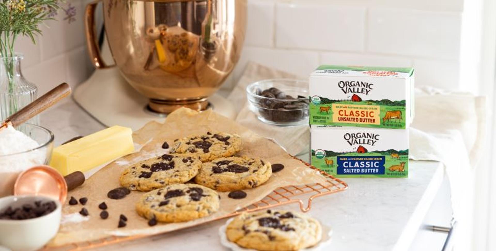 A package of organic salted butter and organic unsalted butter next to chocolate chip cookies.