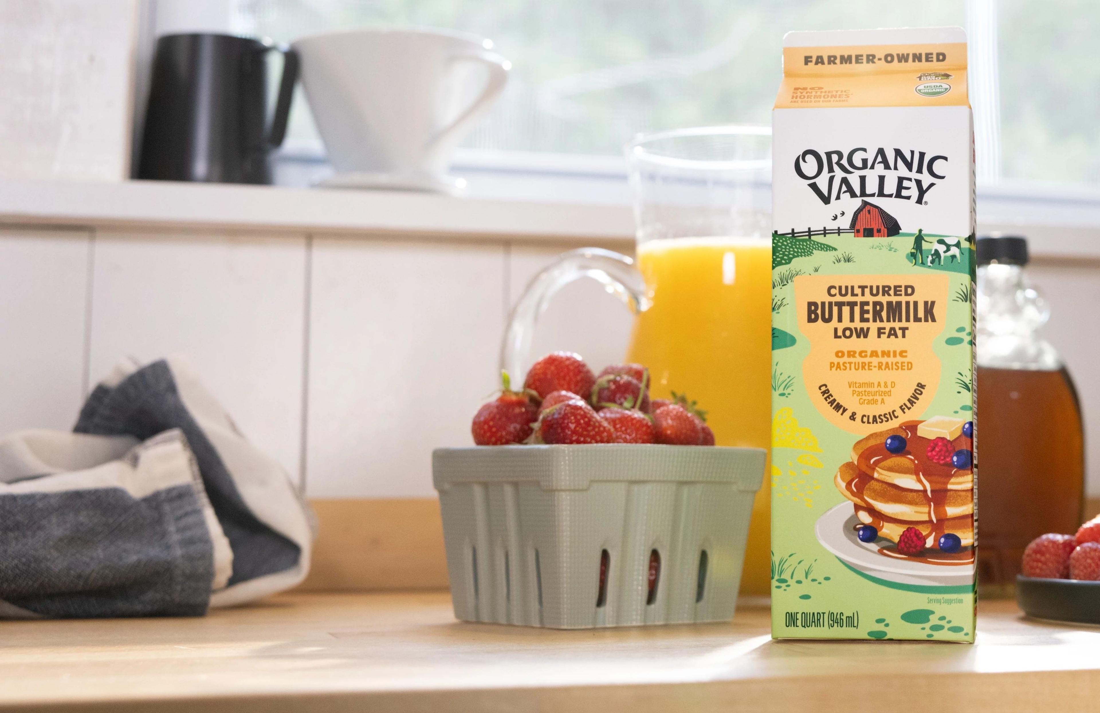 Raspberries, buttermilk and OJ on a counter.