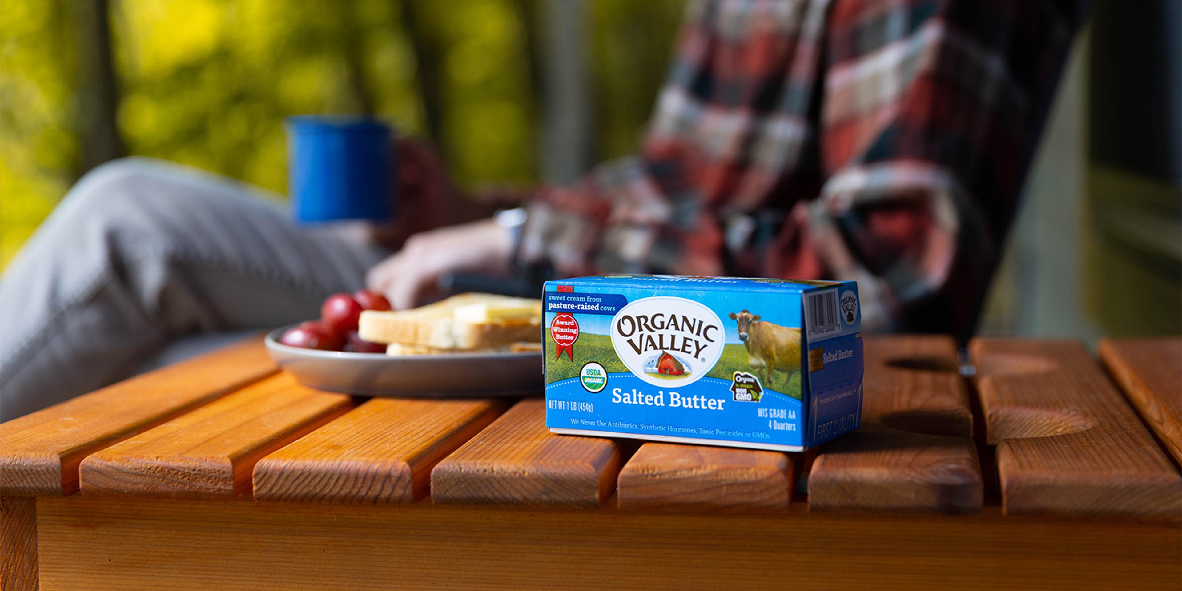 Organic salted butter on a table with toast;  a man drinks coffee in the background.