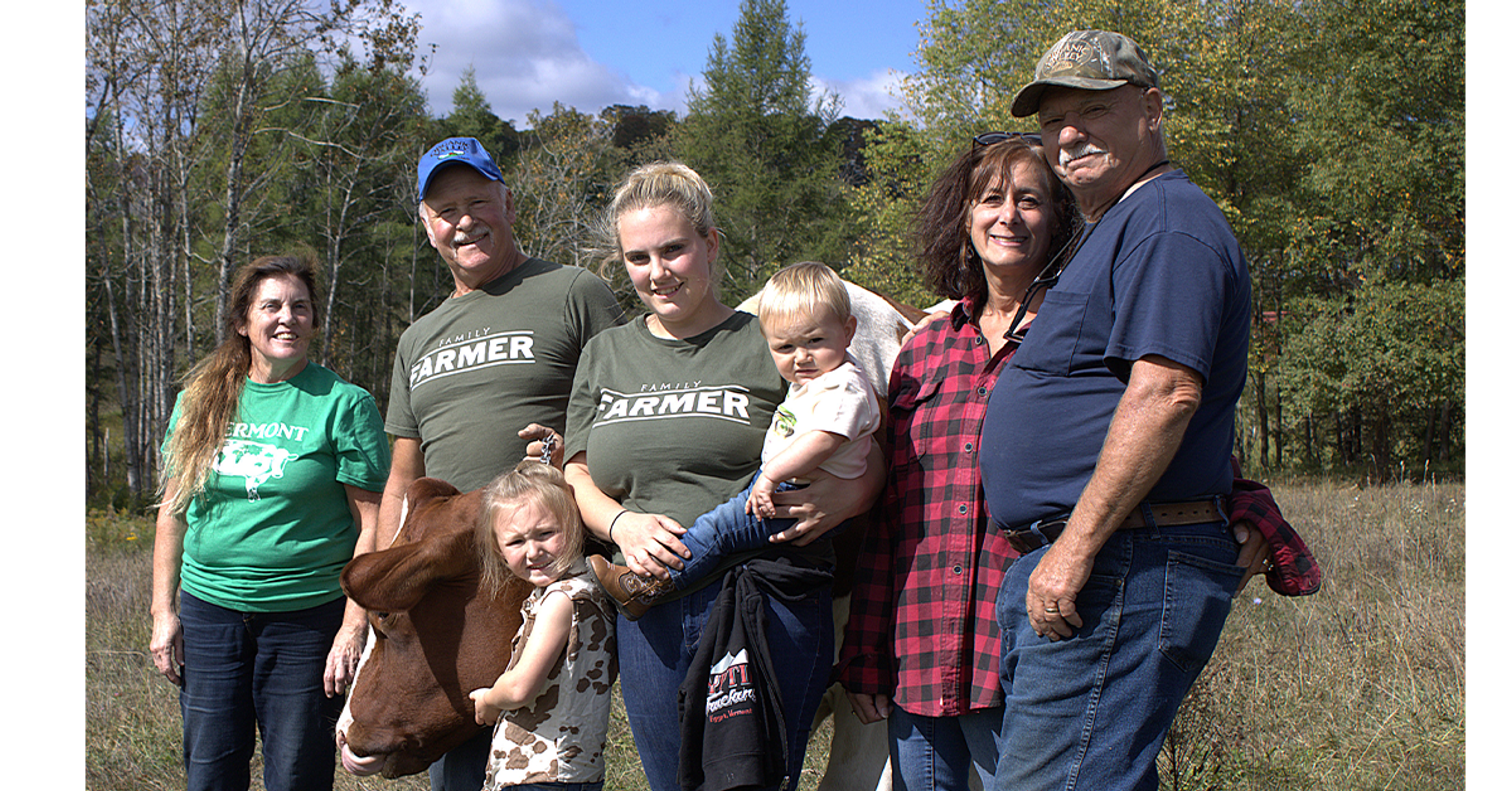 Seven members of the Paris family gather around a cow for a family photo.