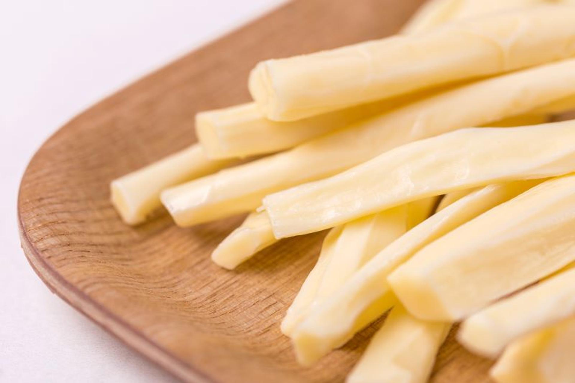 Pieces of string cheese on a wooden platter.