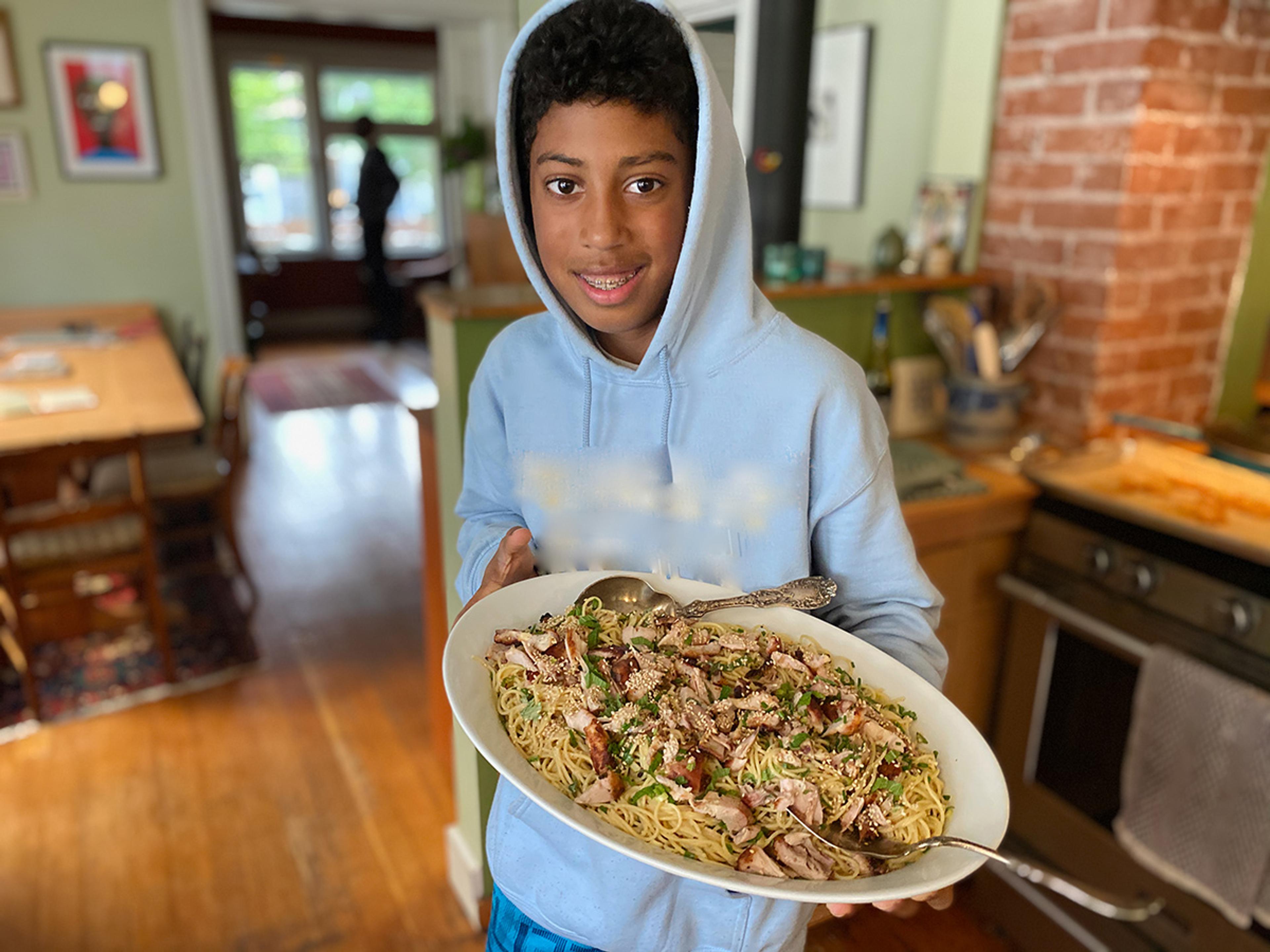 Teenage boy holds up a casserole dish he made.