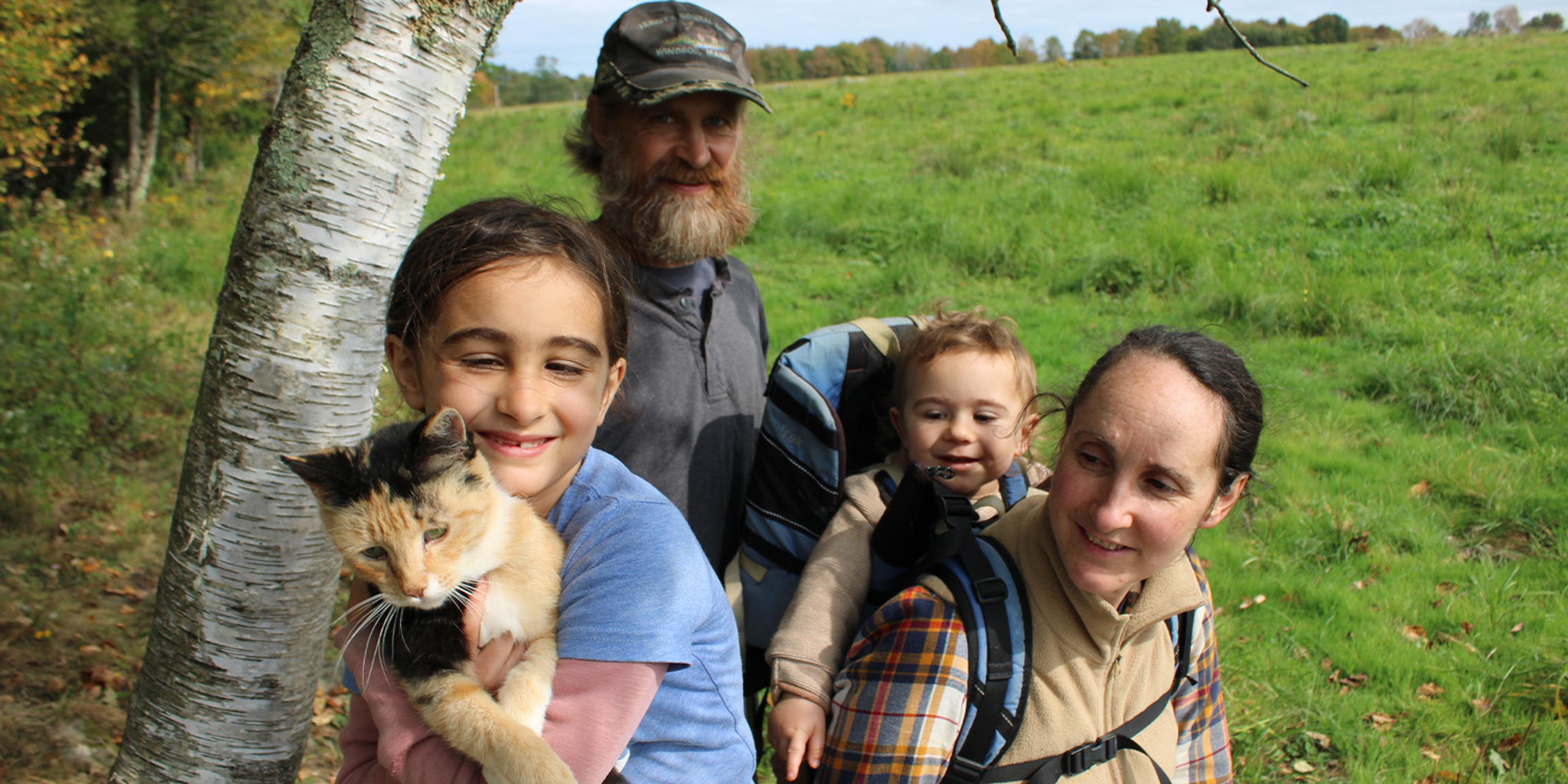 Four members of the Clark, Webb Clark family pose and a girl holds a cat on their Maine farm. 