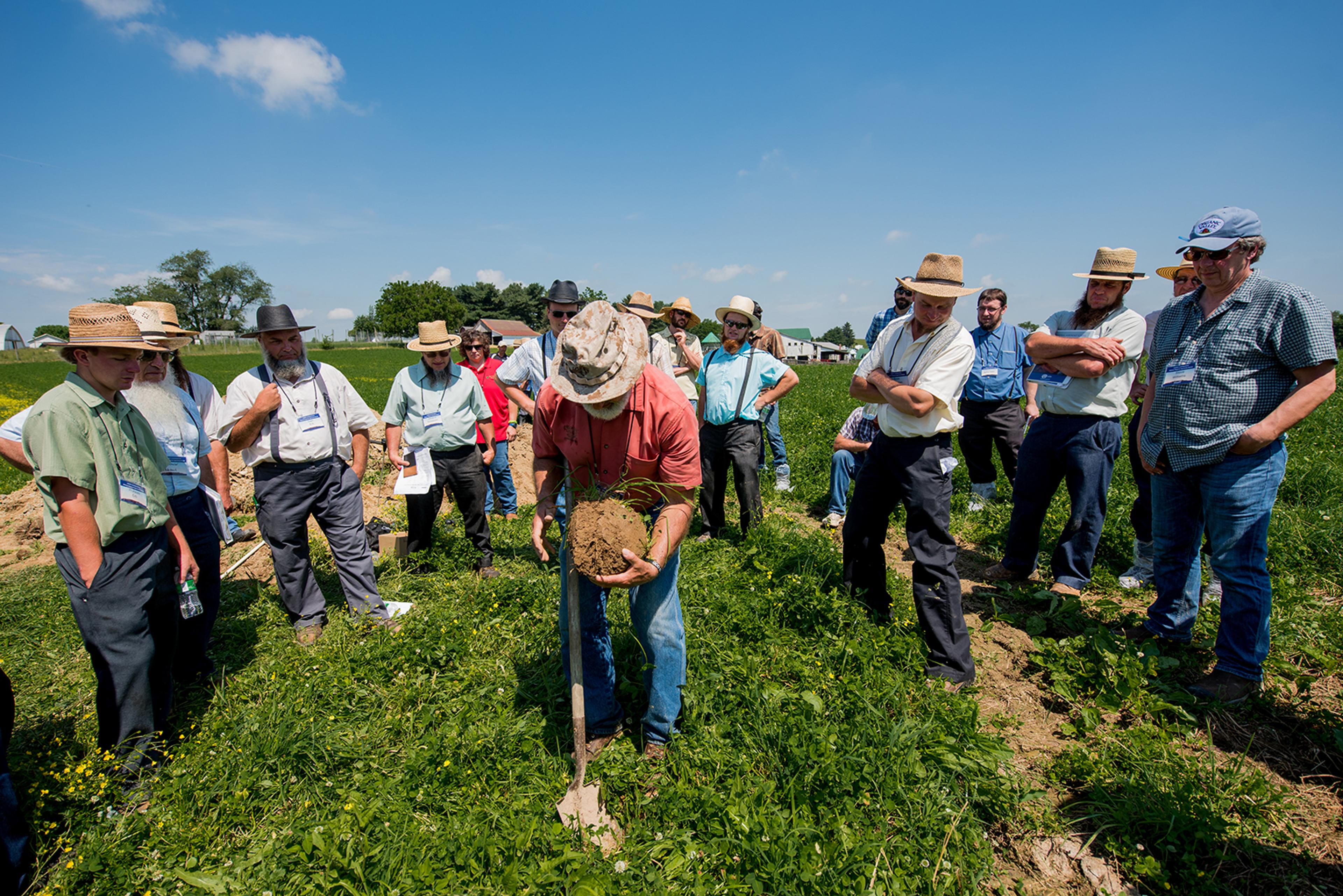 Organic Valley farmers gather around Soil Agronomist Mark Kopecky on a blue-sky day at a soil and pasture workshop in Ohio.