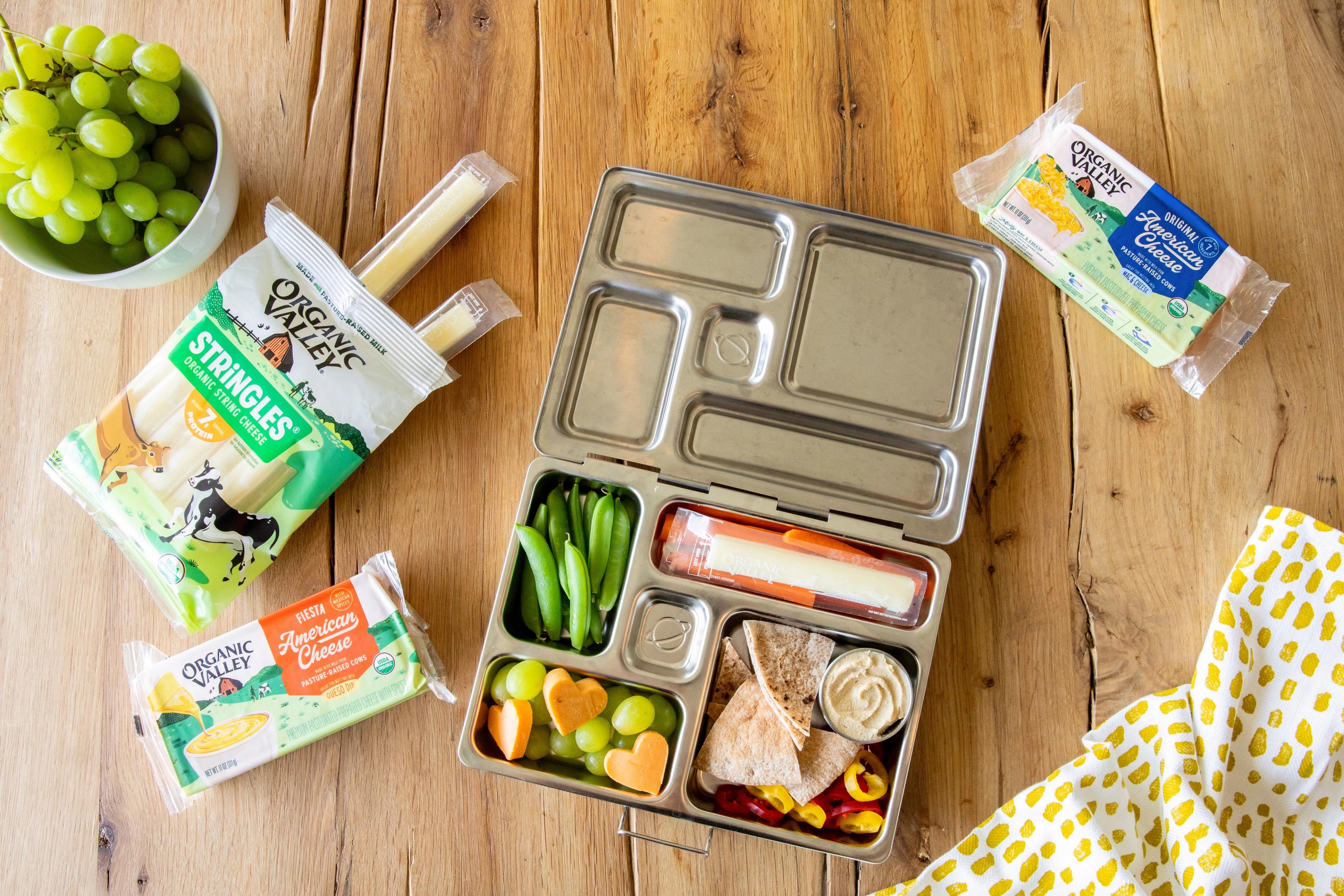 A bento box with cheese, fruit, beans