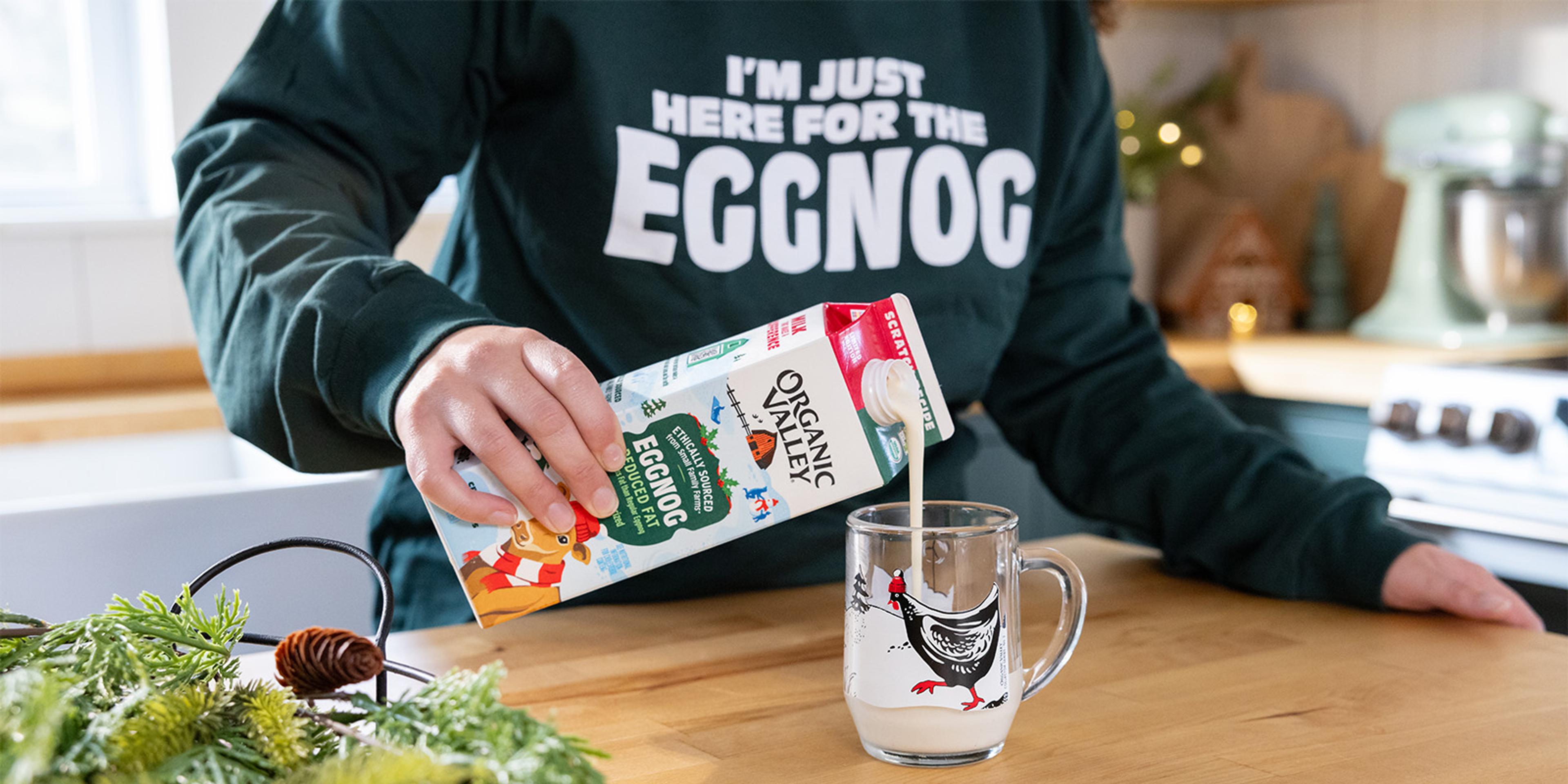 A person pours organic eggnog into a mug.