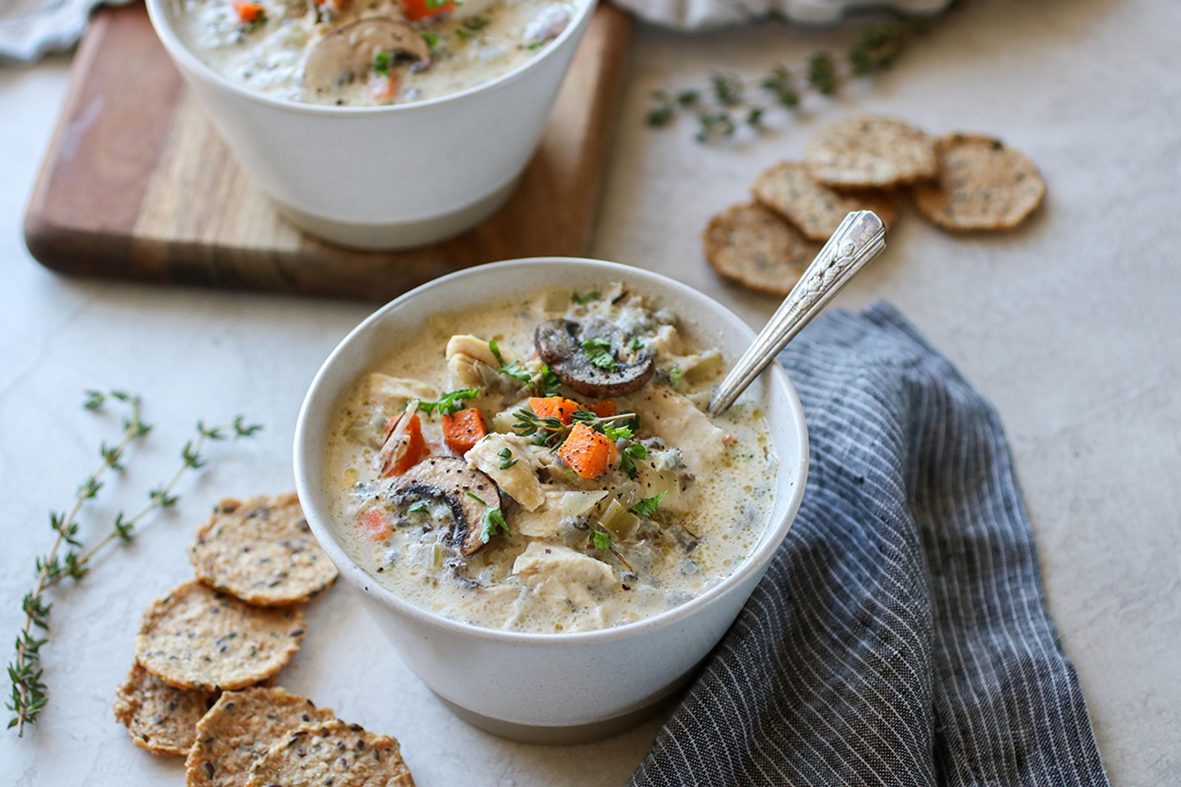 A hearty chicken and wild rice soup loaded with chicken, carrots, and mushrooms, topped with a sprinkle of pepper.