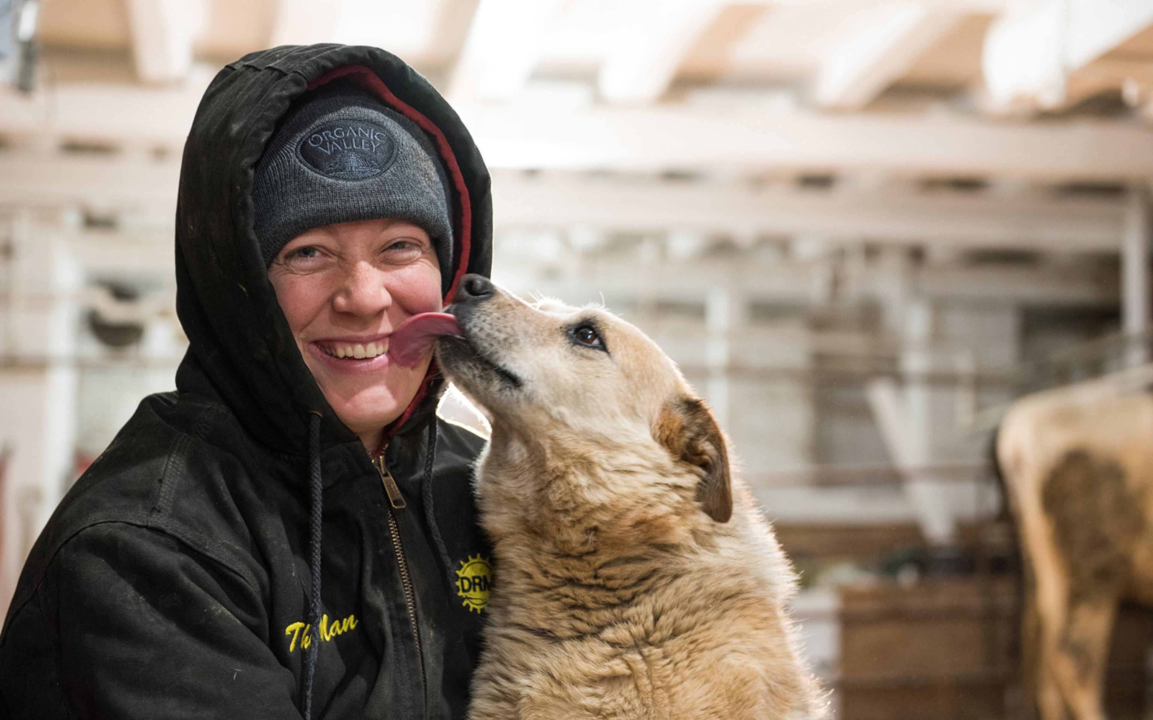 Amy Koenig gets a wet kiss from the Jumpin’ Jerseys farm dog.